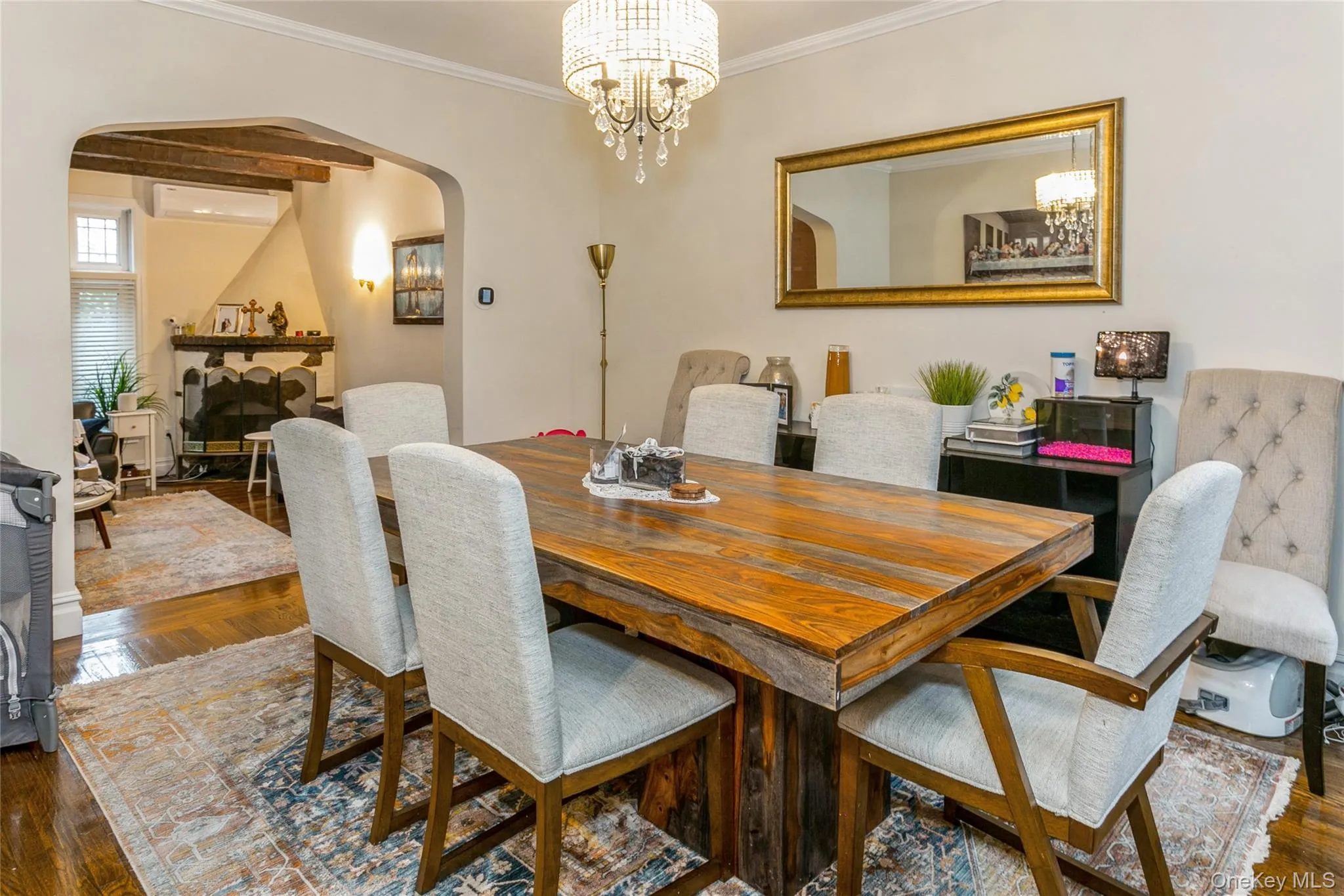 Dining area featuring arched walkways, dark wood-type flooring, ornamental molding, a chandelier, and a wall unit AC Dining area featuring arched walkways, dark wood-type flooring, ornamental molding, a chandelier, and a wall unit AC