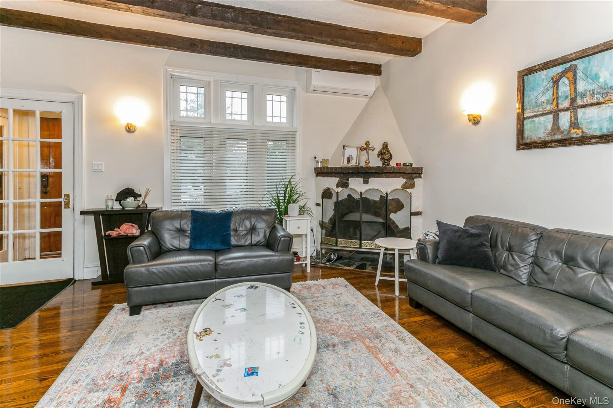Living area with dark wood-type flooring, beam ceiling, a fireplace, and a wall mounted air conditioner Living area with dark wood-type flooring, beam ceiling, a fireplace, and a wall mounted air conditioner