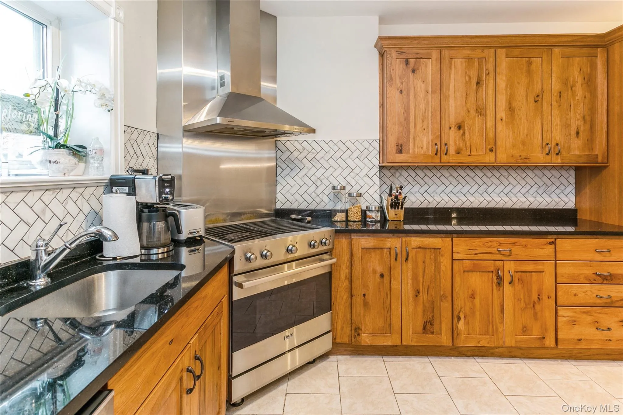 Kitchen with brown cabinetry, dark stone counters, extractor fan, and high end stainless steel range oven Kitchen with brown cabinetry, dark stone counters, extractor fan, and high end stainless steel range oven