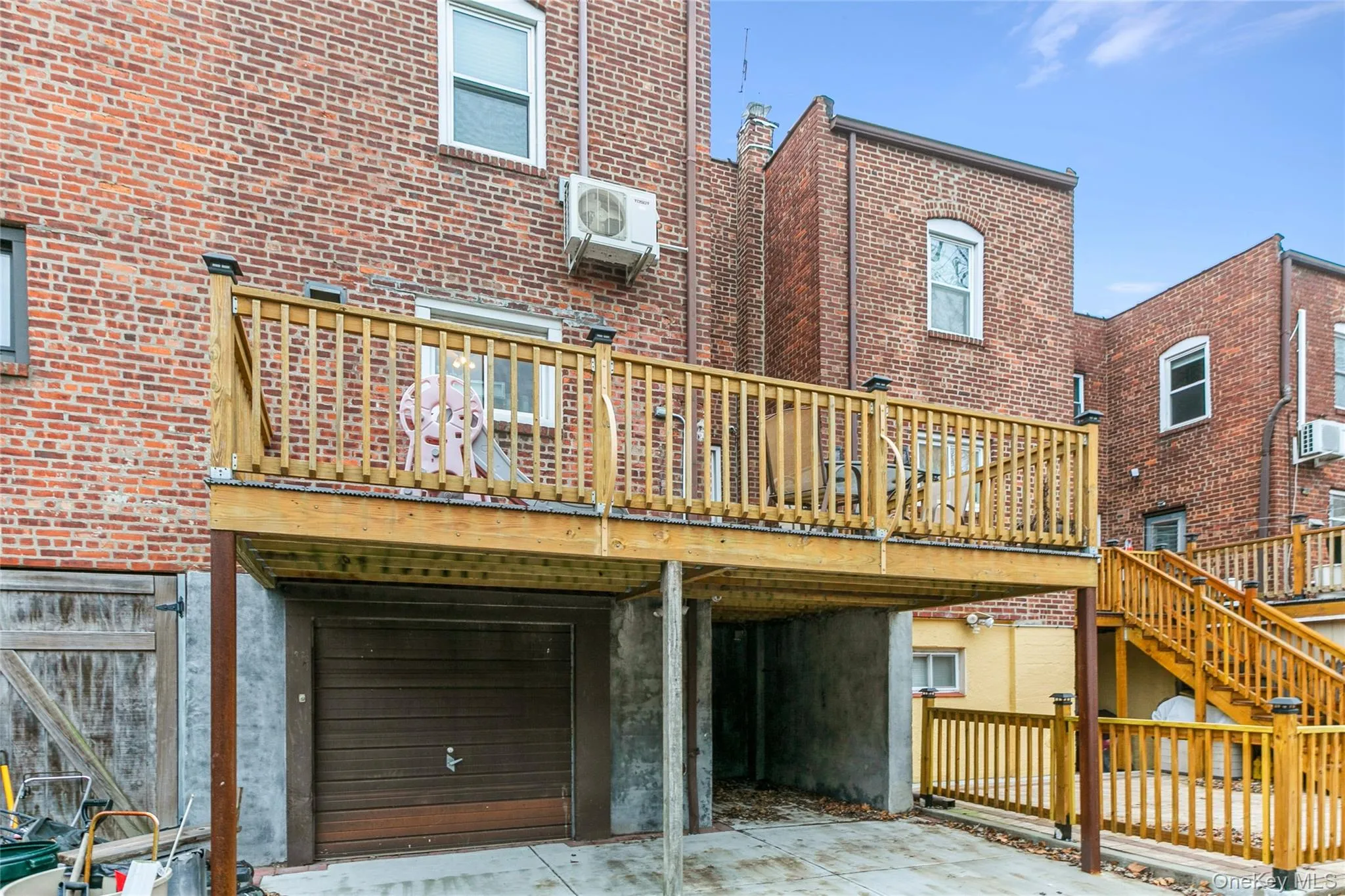 Back of house featuring a deck, brick siding, and a garage Back of house featuring a deck, brick siding, and a garage