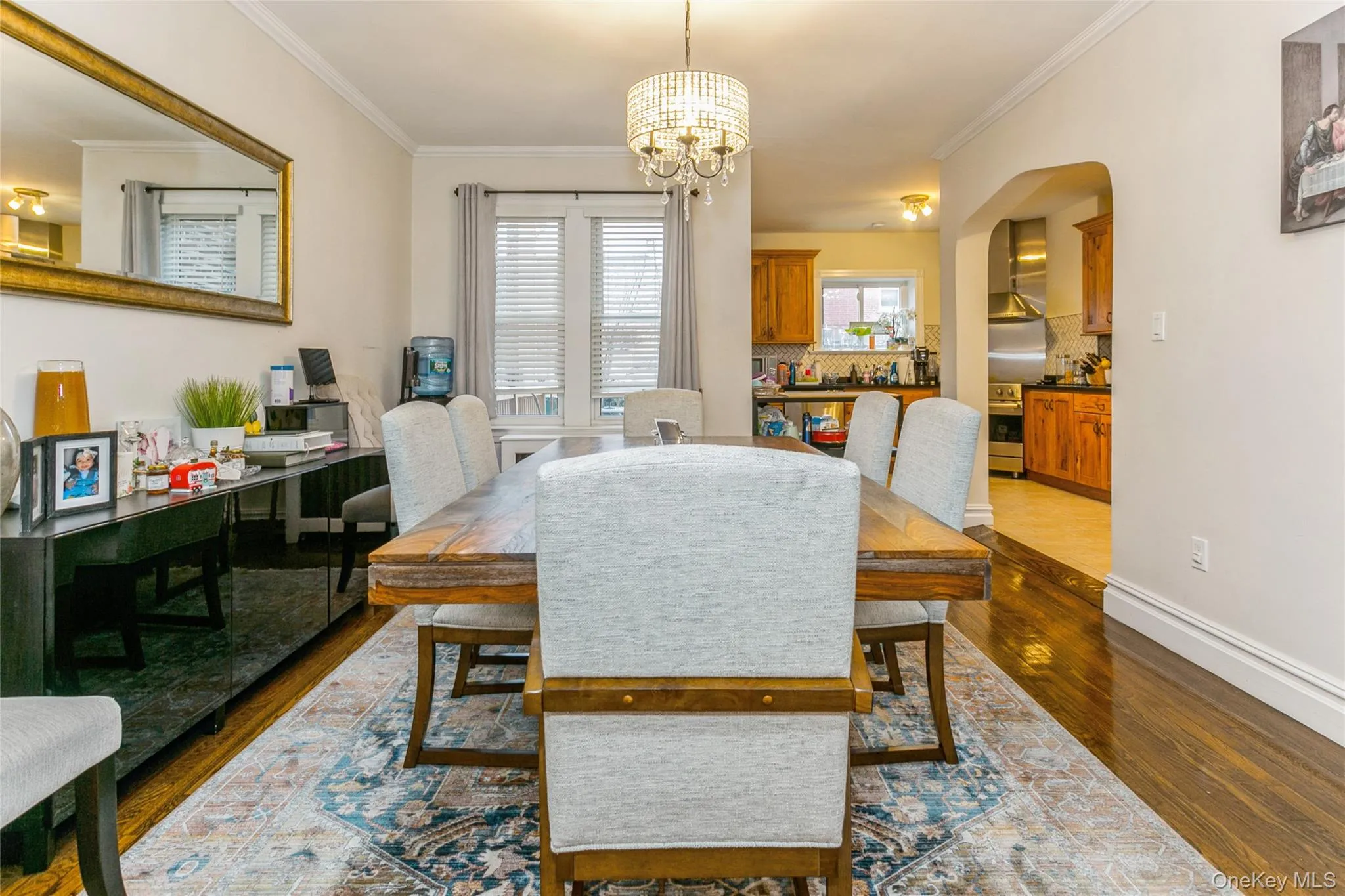 Dining space featuring crown molding, a chandelier, dark wood-style flooring, and arched walkways Dining space featuring crown molding, a chandelier, dark wood-style flooring, and arched walkways