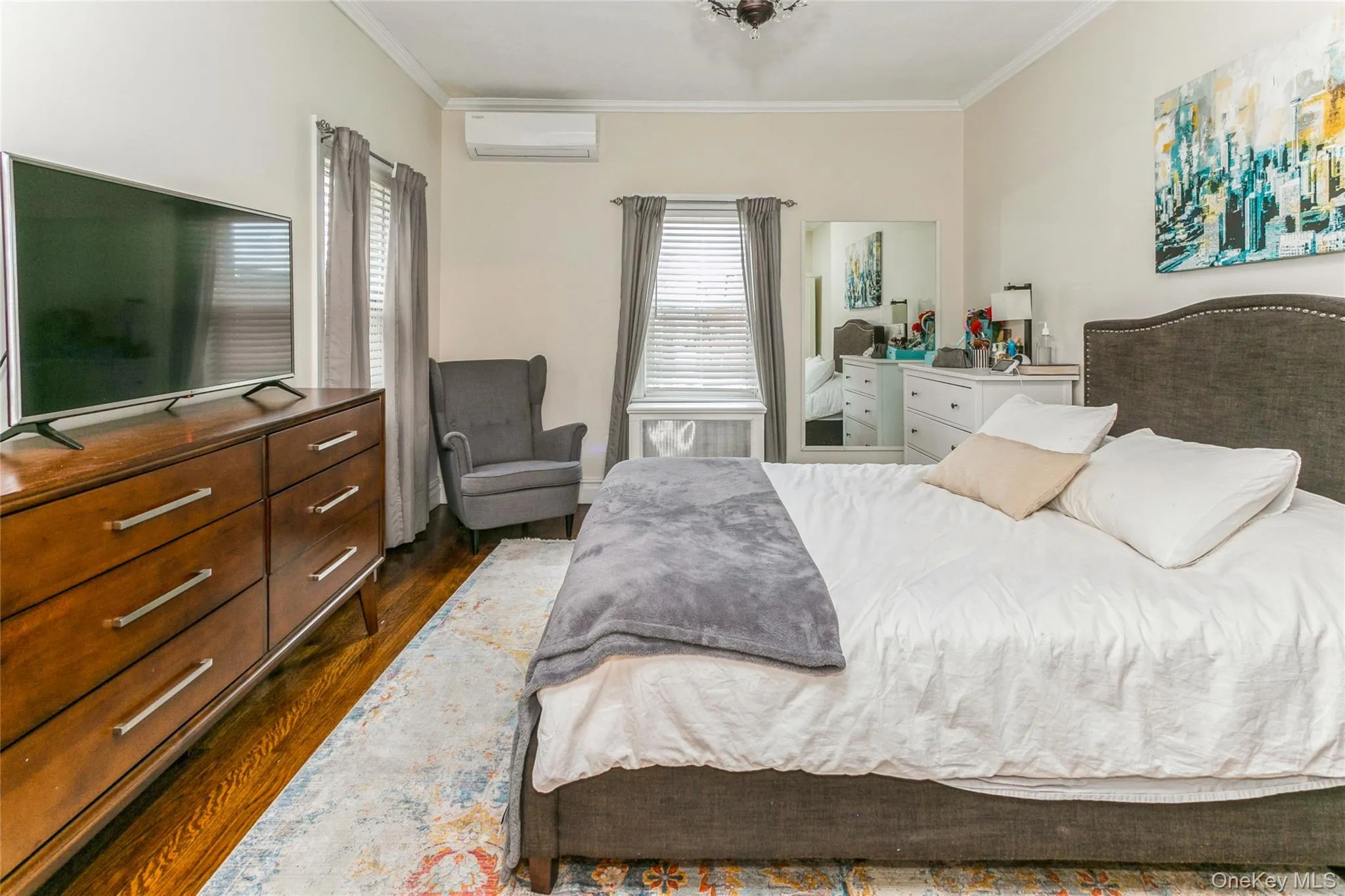 Bedroom featuring dark wood-type flooring, ornamental molding, and a wall unit AC Bedroom featuring dark wood-type flooring, ornamental molding, and a wall unit AC