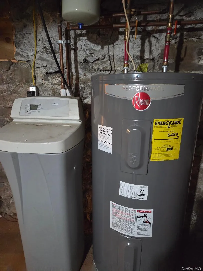 Utility room featuring electric water heater and softener newer unit. Utility room featuring electric water heater and softener newer unit.