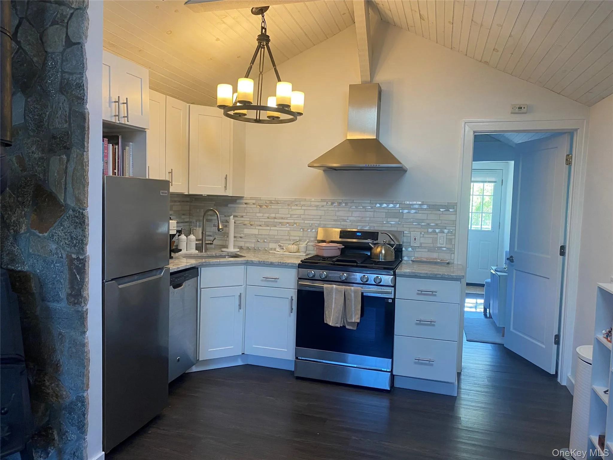 Kitchen featuring white cabinetry, stainless steel appliances, wall chimney exhaust hood, dark wood laminate flooring. Kitchen featuring white cabinetry, stainless steel appliances, wall chimney exhaust hood, dark wood laminate flooring.