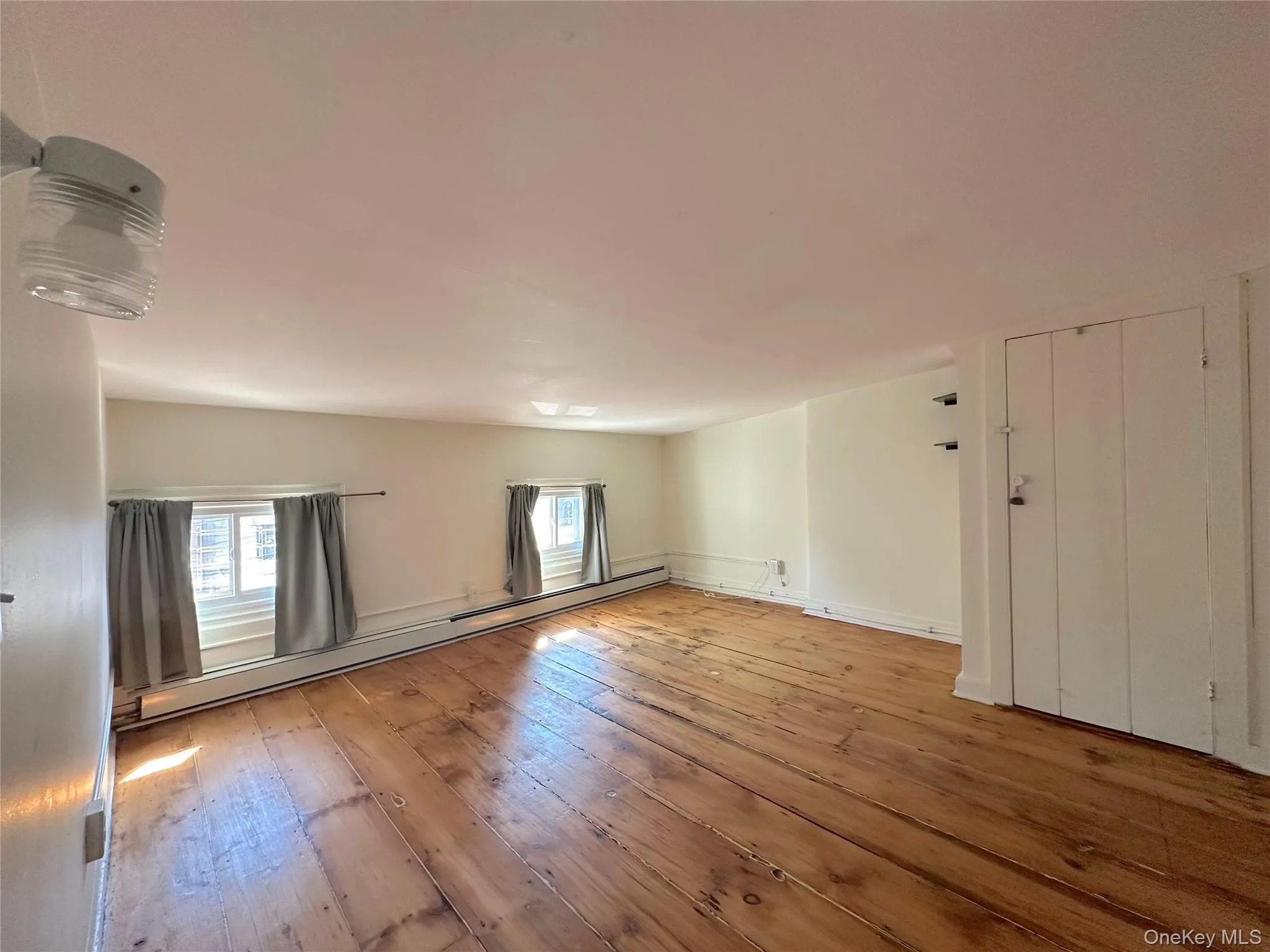 Spare room with a baseboard heating unit, wood-type flooring, and plenty of natural light Spare room with a baseboard heating unit, wood-type flooring, and plenty of natural light