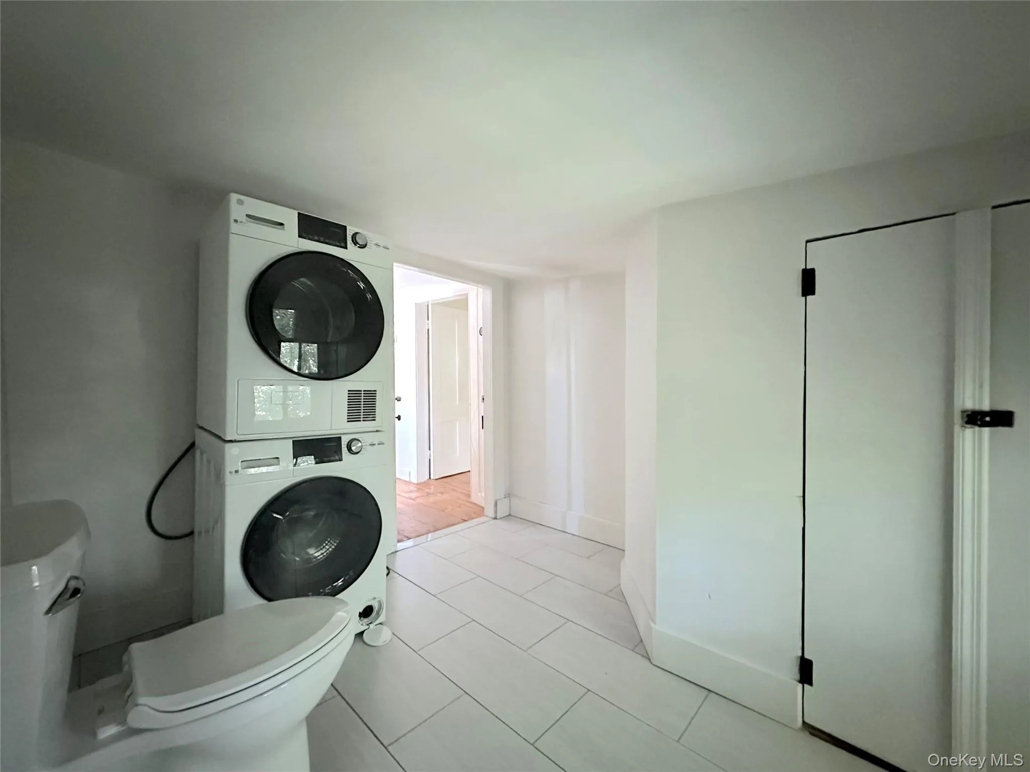 Bathroom featuring estacked washer and dryer and light tile patterned floors Bathroom featuring estacked washer and dryer and light tile patterned floors