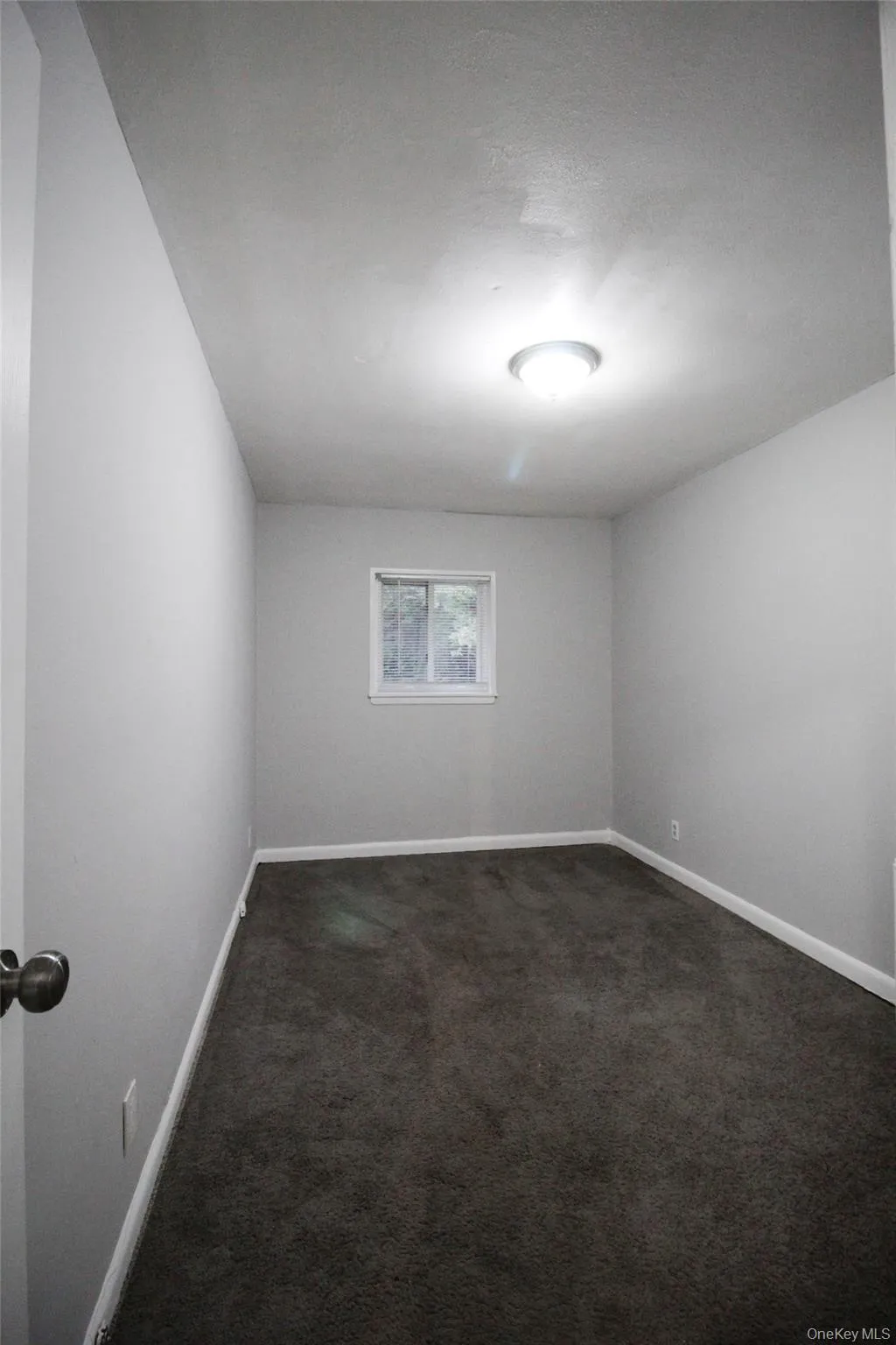 Unfurnished room featuring dark colored carpet and a textured ceiling Unfurnished room featuring dark colored carpet and a textured ceiling