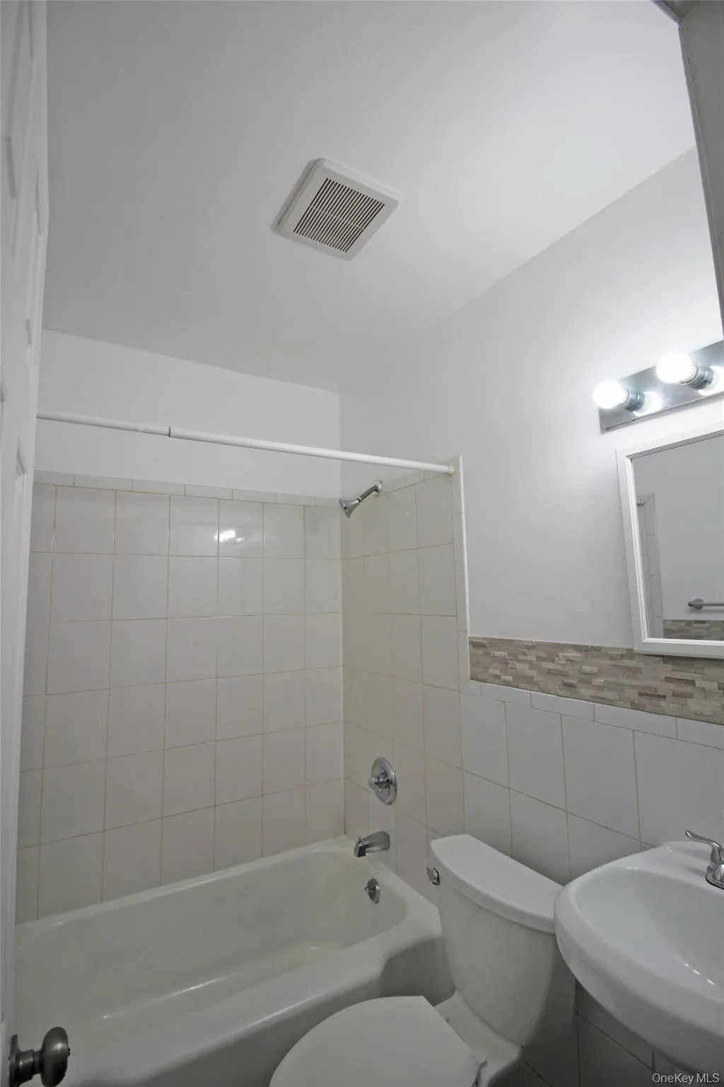 Full bathroom with tile walls, bathing tub / shower combination, and wainscoting Full bathroom with tile walls, bathing tub / shower combination, and wainscoting