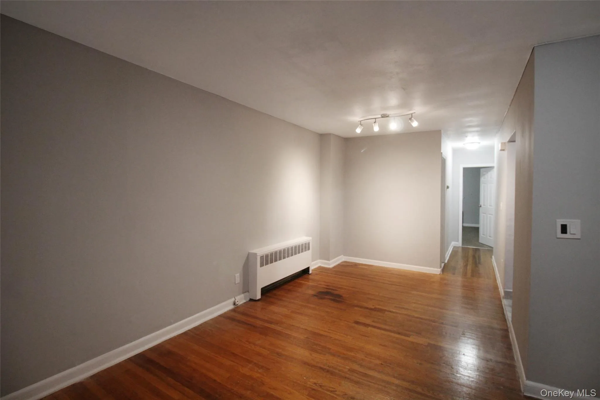 Spare room with radiator heating unit and dark wood-style flooring Spare room with radiator heating unit and dark wood-style flooring