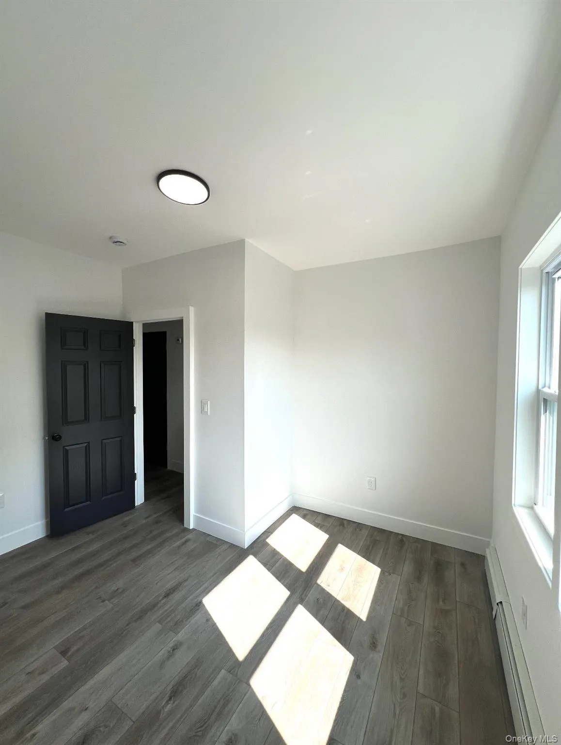 Unfurnished bedroom featuring a baseboard radiator and dark wood-style flooring Unfurnished bedroom featuring a baseboard radiator and dark wood-style flooring