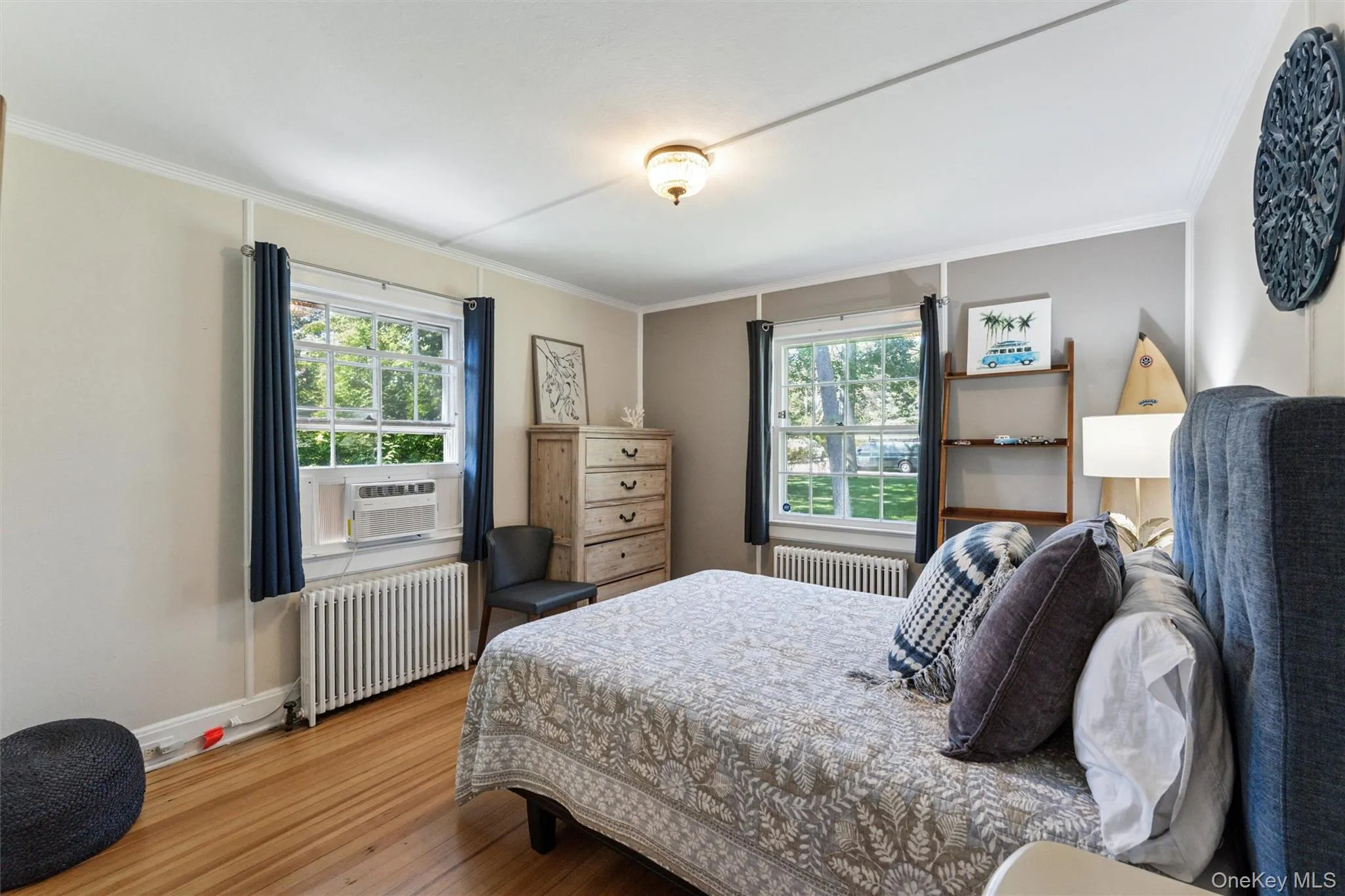 Bedroom with radiator, multiple windows, wood finished floors, and ornamental molding Bedroom with radiator, multiple windows, wood finished floors, and ornamental molding