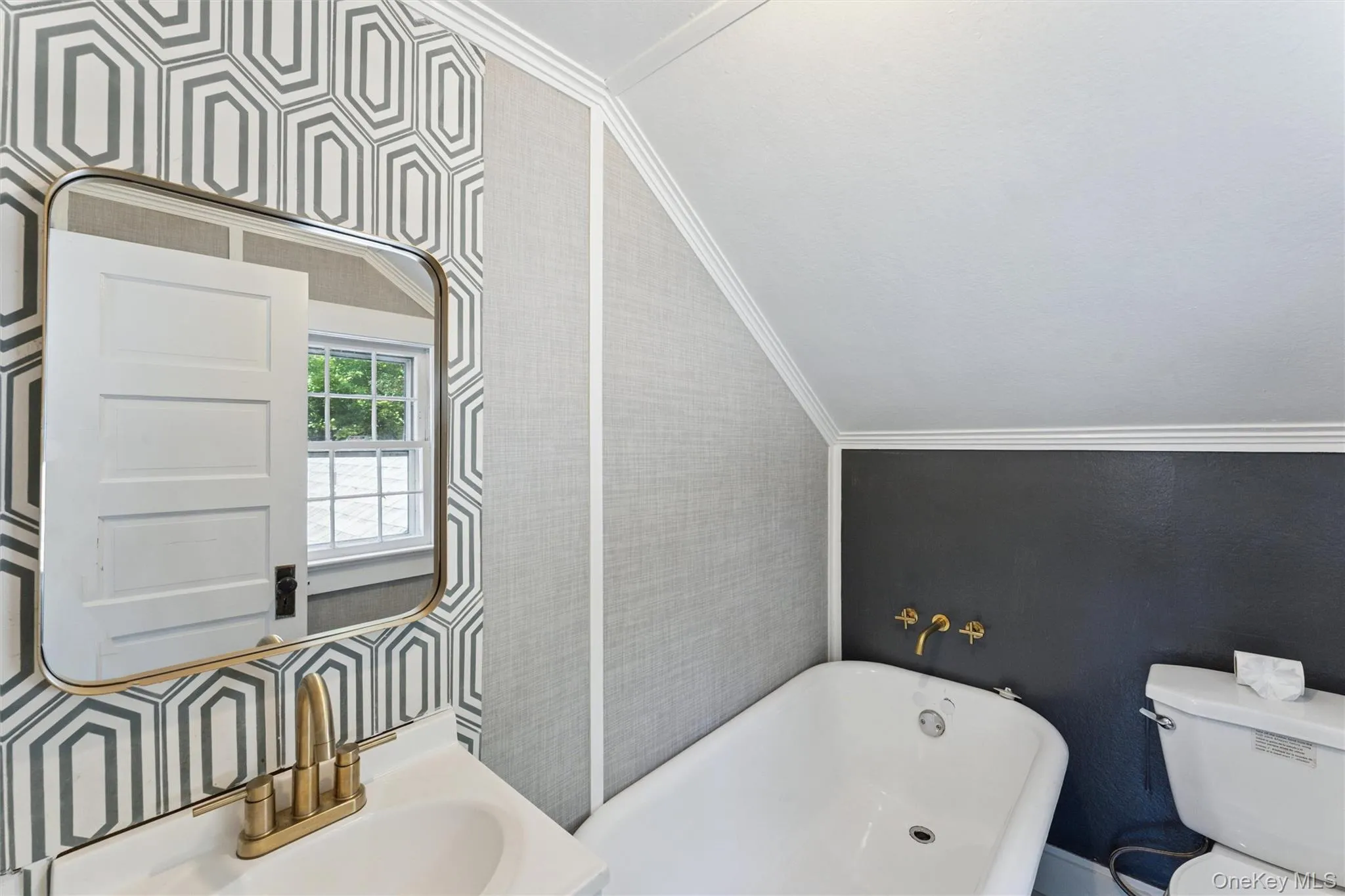 Full bathroom with a soaking tub, wallpapered walls, crown molding, and vaulted ceiling Full bathroom with a soaking tub, wallpapered walls, crown molding, and vaulted ceiling