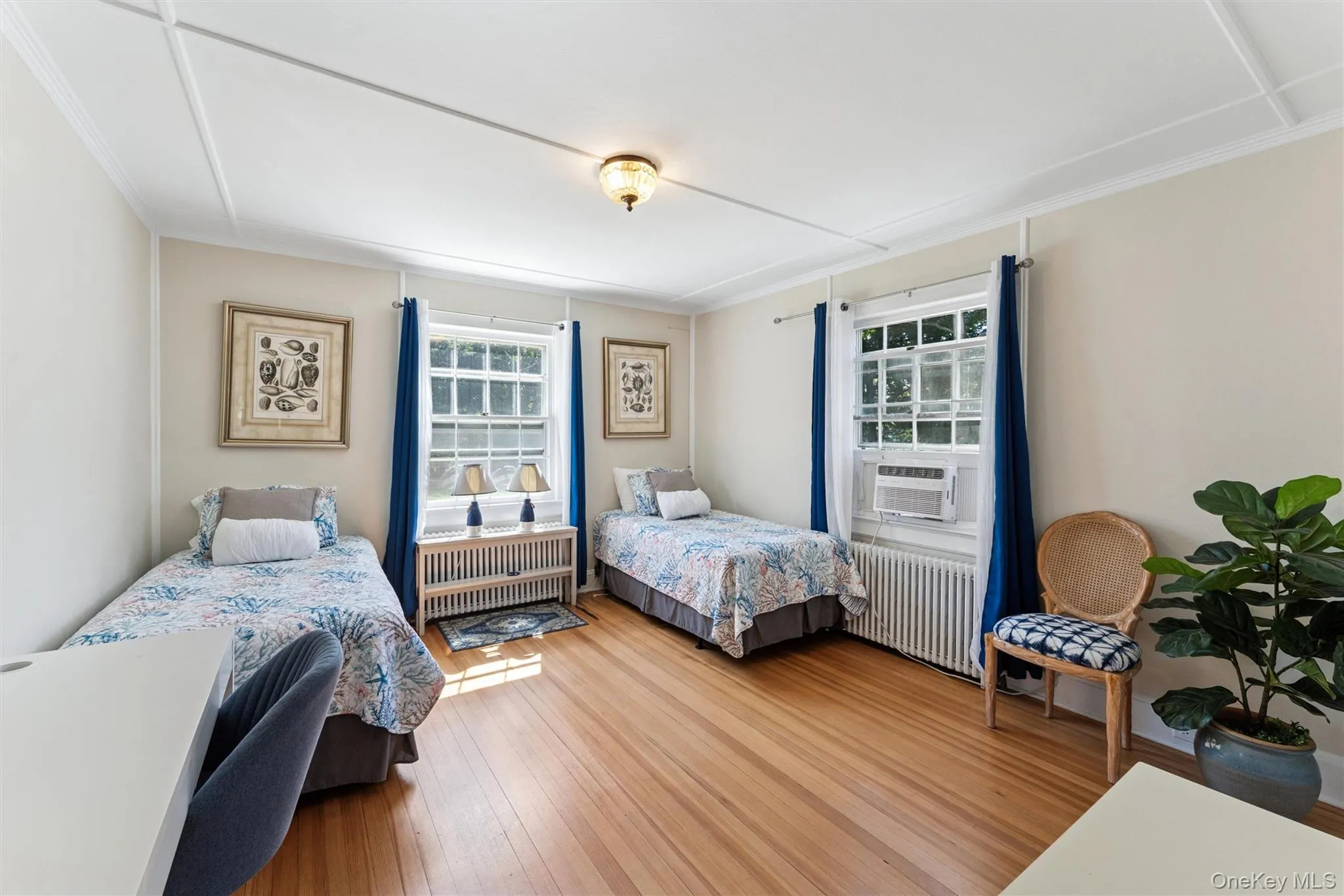 Bedroom with radiator heating unit, wood finished floors, cooling unit, and ornamental molding Bedroom with radiator heating unit, wood finished floors, cooling unit, and ornamental molding