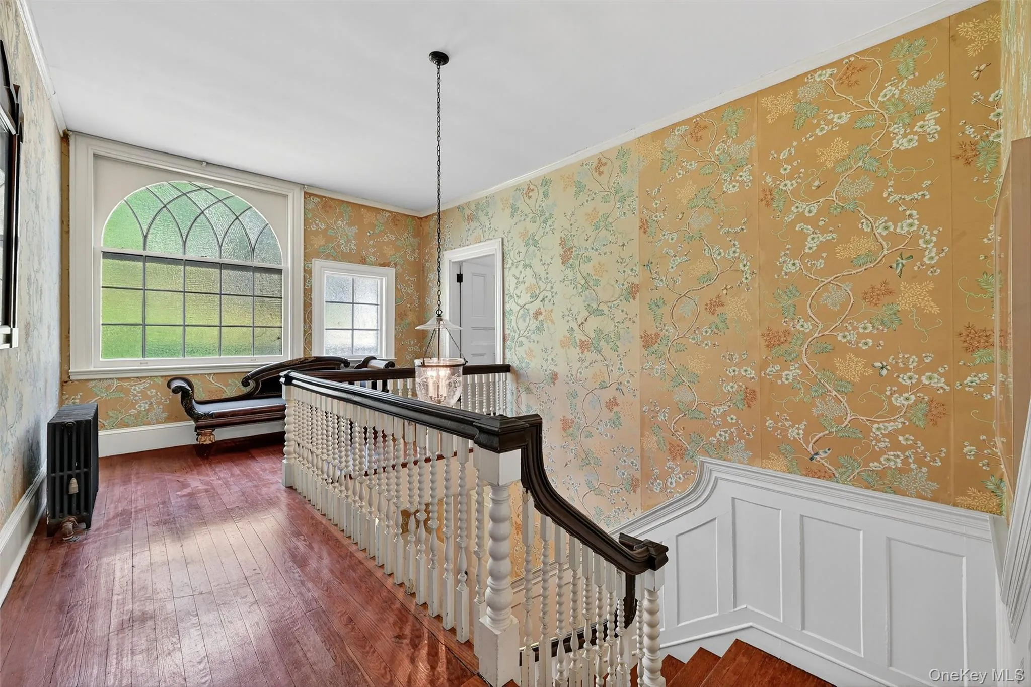 Corridor with wallpapered walls, dark wood-style flooring, radiator heating unit, crown molding, and an upstairs landing Corridor with wallpapered walls, dark wood-style flooring, radiator heating unit, crown molding, and an upstairs landing