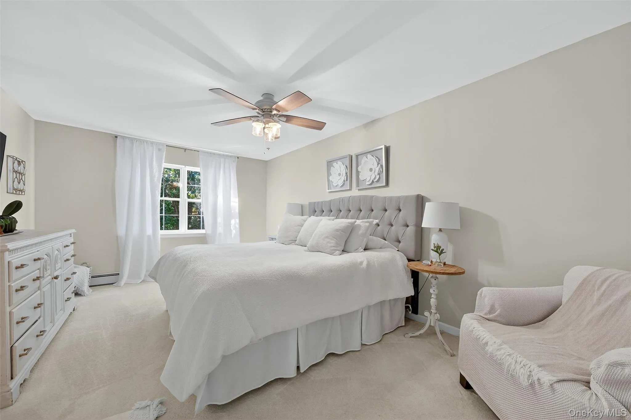 Carpeted bedroom featuring a ceiling fan and baseboard heating Carpeted bedroom featuring a ceiling fan and baseboard heating