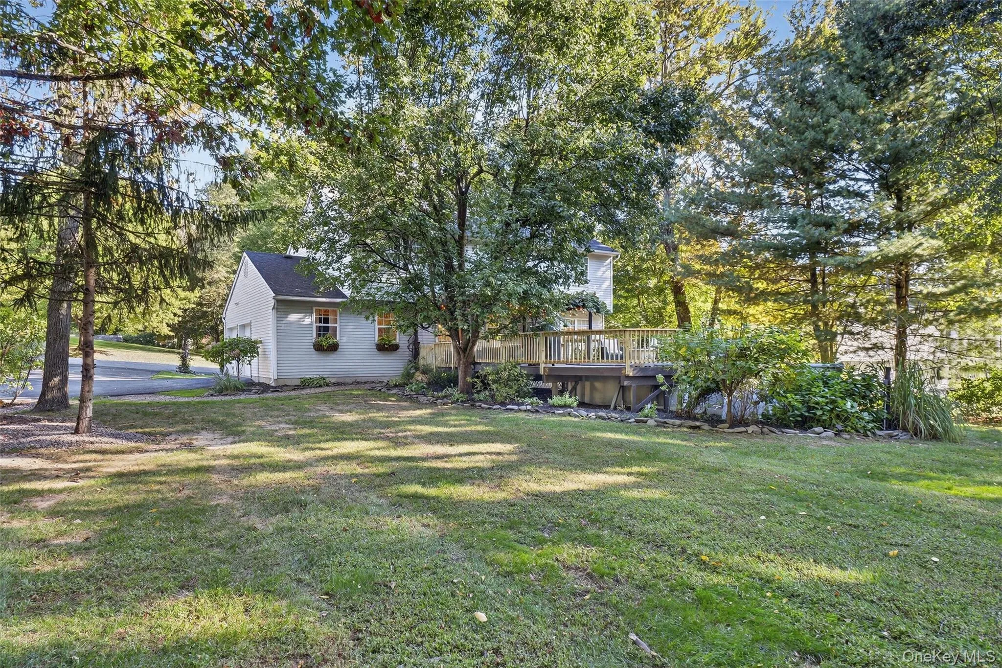 View of grassy yard with a wooden deck and view of scattered trees View of grassy yard with a wooden deck and view of scattered trees