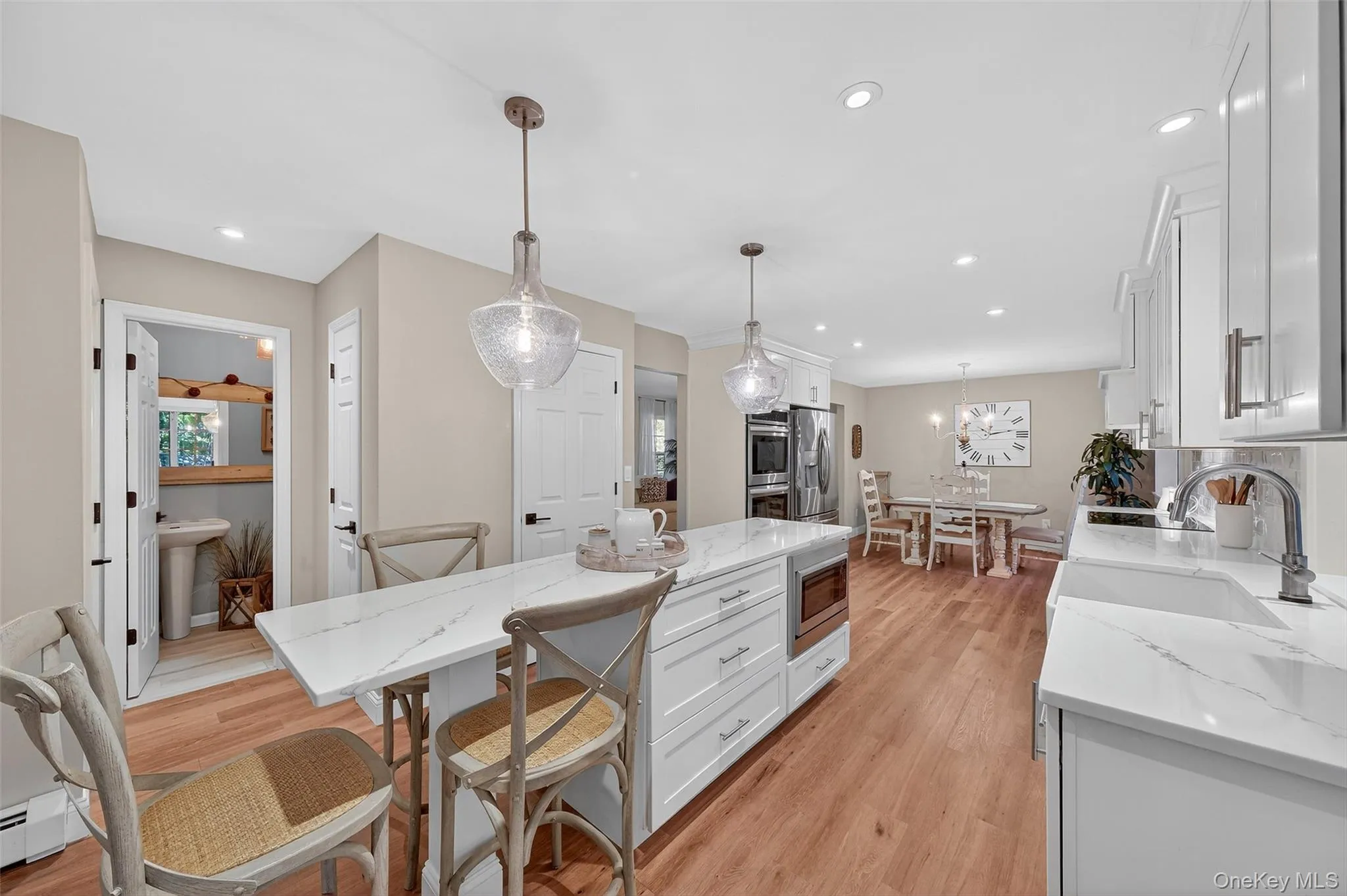 Kitchen featuring light stone countertops, white cabinetry, decorative light fixtures, a breakfast bar, and recessed lighting Kitchen featuring light stone countertops, white cabinetry, decorative light fixtures, a breakfast bar, and recessed lighting