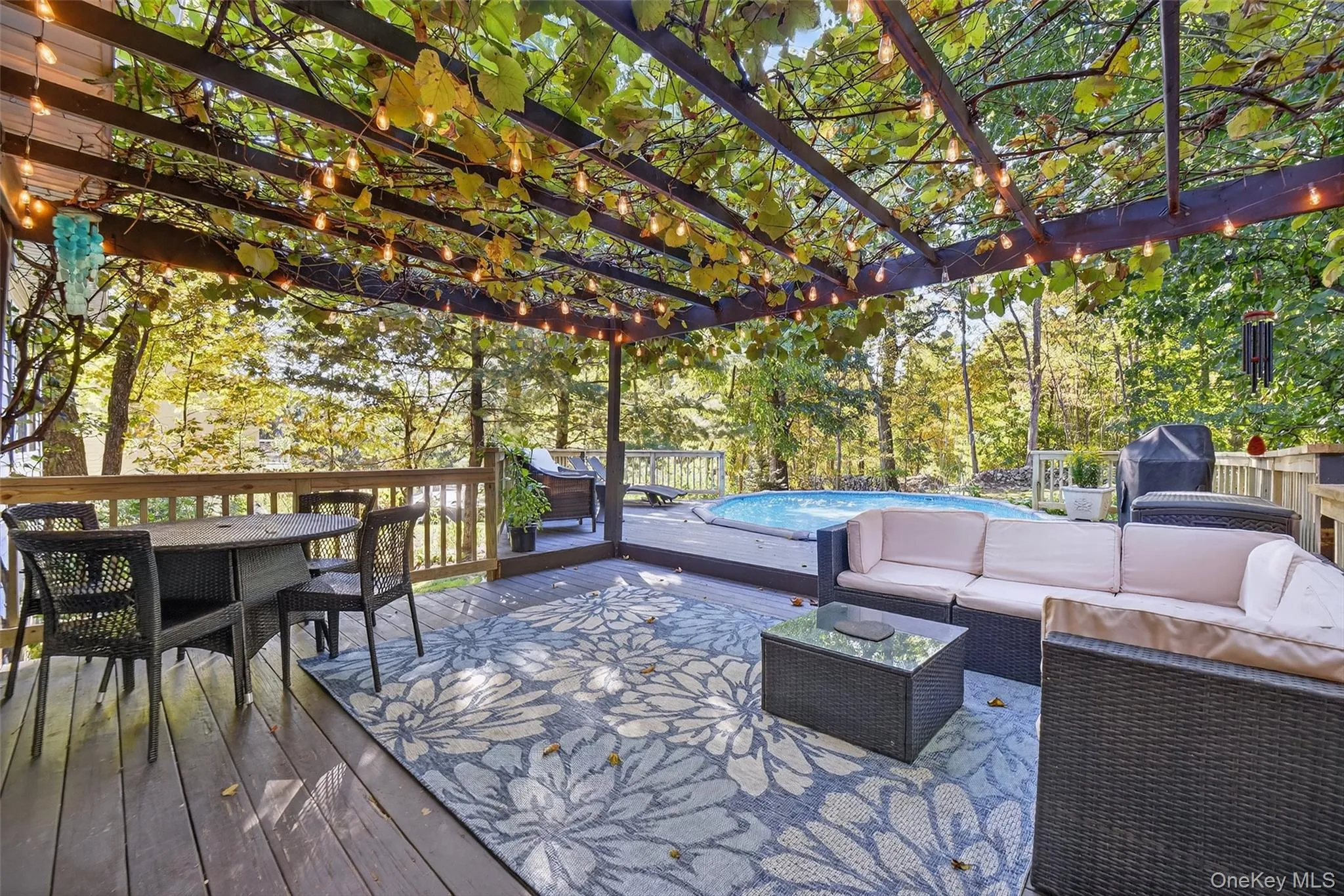 Wooden deck with outdoor dining area, outdoor lounge area, an outdoor pool, and view of wooded area Wooden deck with outdoor dining area, outdoor lounge area, an outdoor pool, and view of wooded area