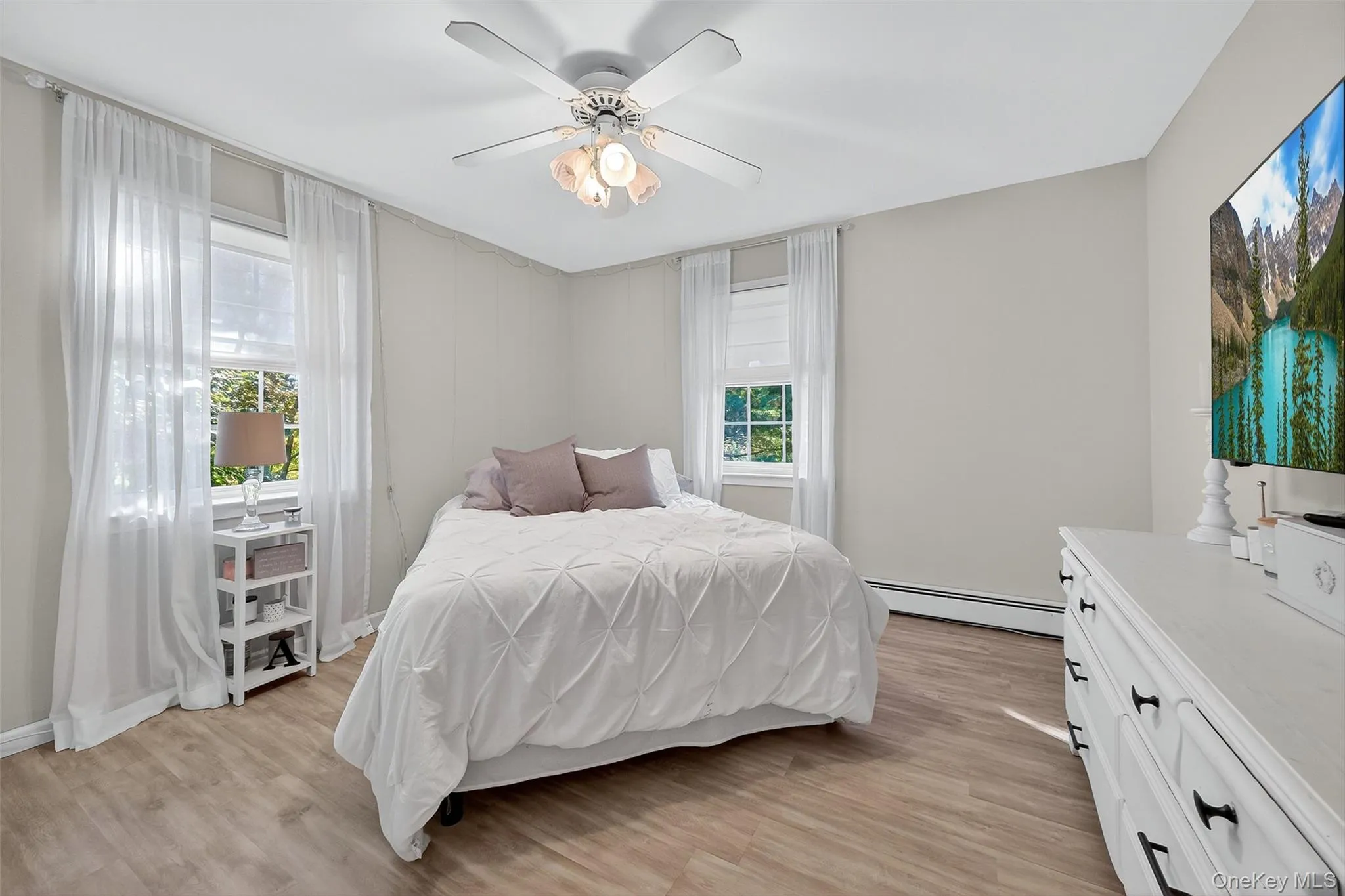 Bedroom featuring light wood-style floors, a baseboard radiator, and ceiling fan Bedroom featuring light wood-style floors, a baseboard radiator, and ceiling fan