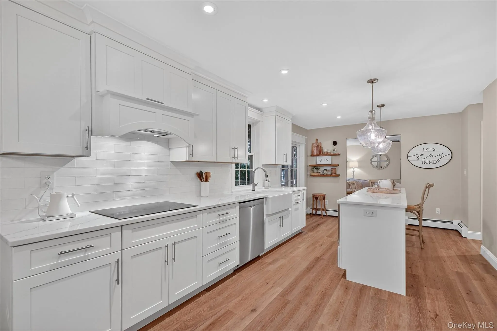Kitchen featuring decorative light fixtures, white cabinetry, backsplash, light wood-style floors, and recessed lighting Kitchen featuring decorative light fixtures, white cabinetry, backsplash, light wood-style floors, and recessed lighting