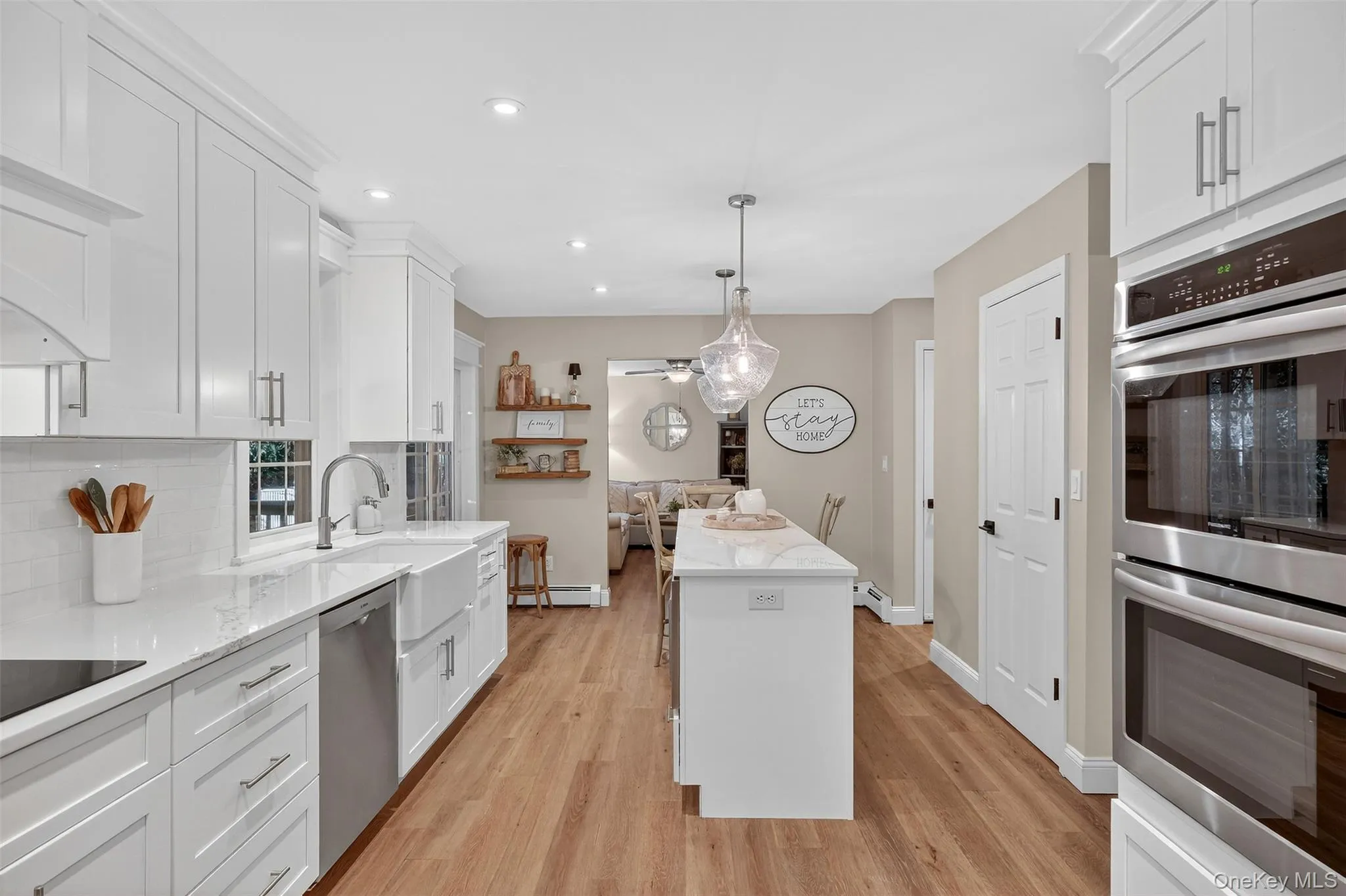 Kitchen with stainless steel appliances, white cabinets, a center island, tasteful backsplash, and light stone counters Kitchen with stainless steel appliances, white cabinets, a center island, tasteful backsplash, and light stone counters