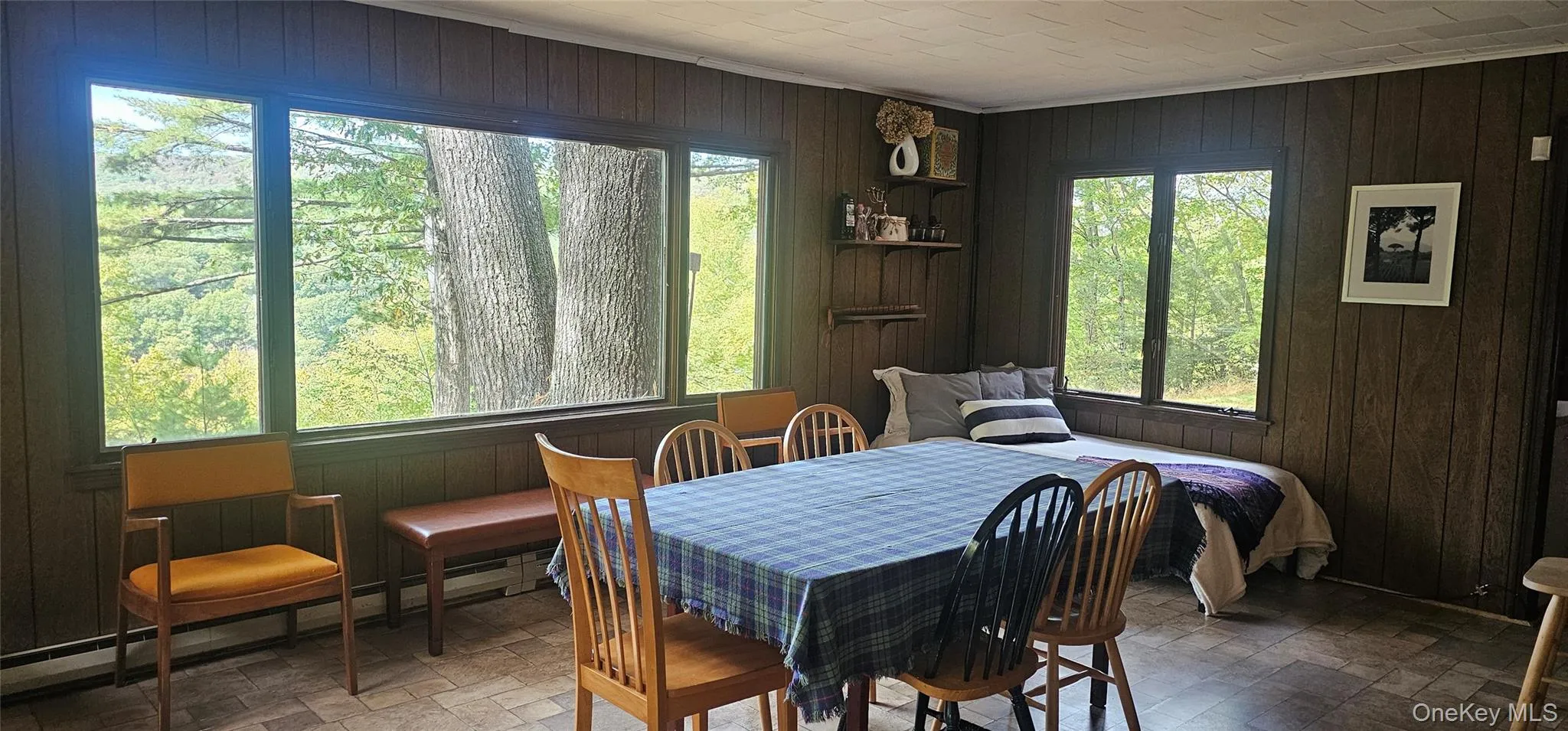 Dining area featuring wooden walls, a baseboard heating unit, stone finish floors, and ornamental molding Dining area featuring wooden walls, a baseboard heating unit, stone finish floors, and ornamental molding