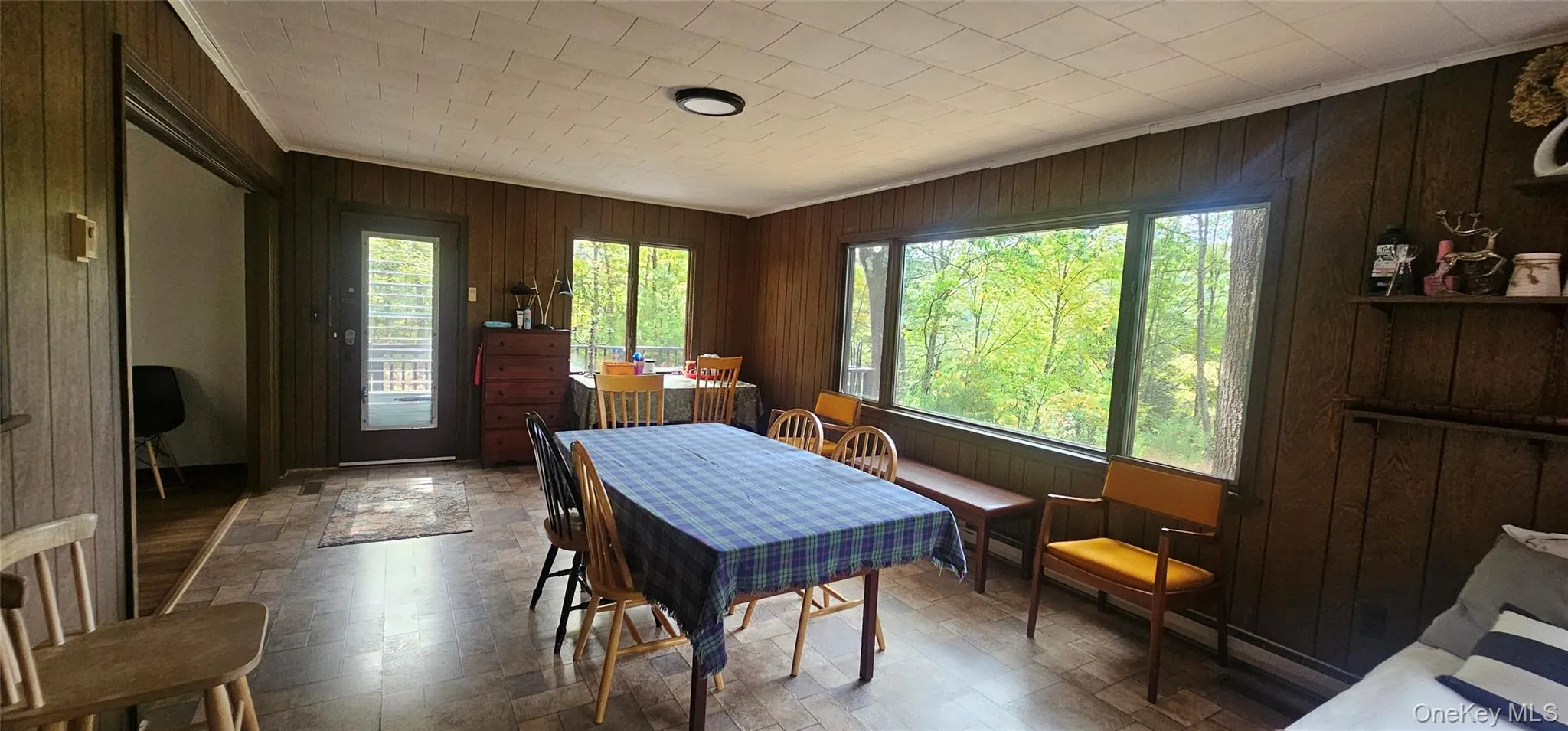 Dining area with wooden walls, crown molding, and stone finish floors Dining area with wooden walls, crown molding, and stone finish floors