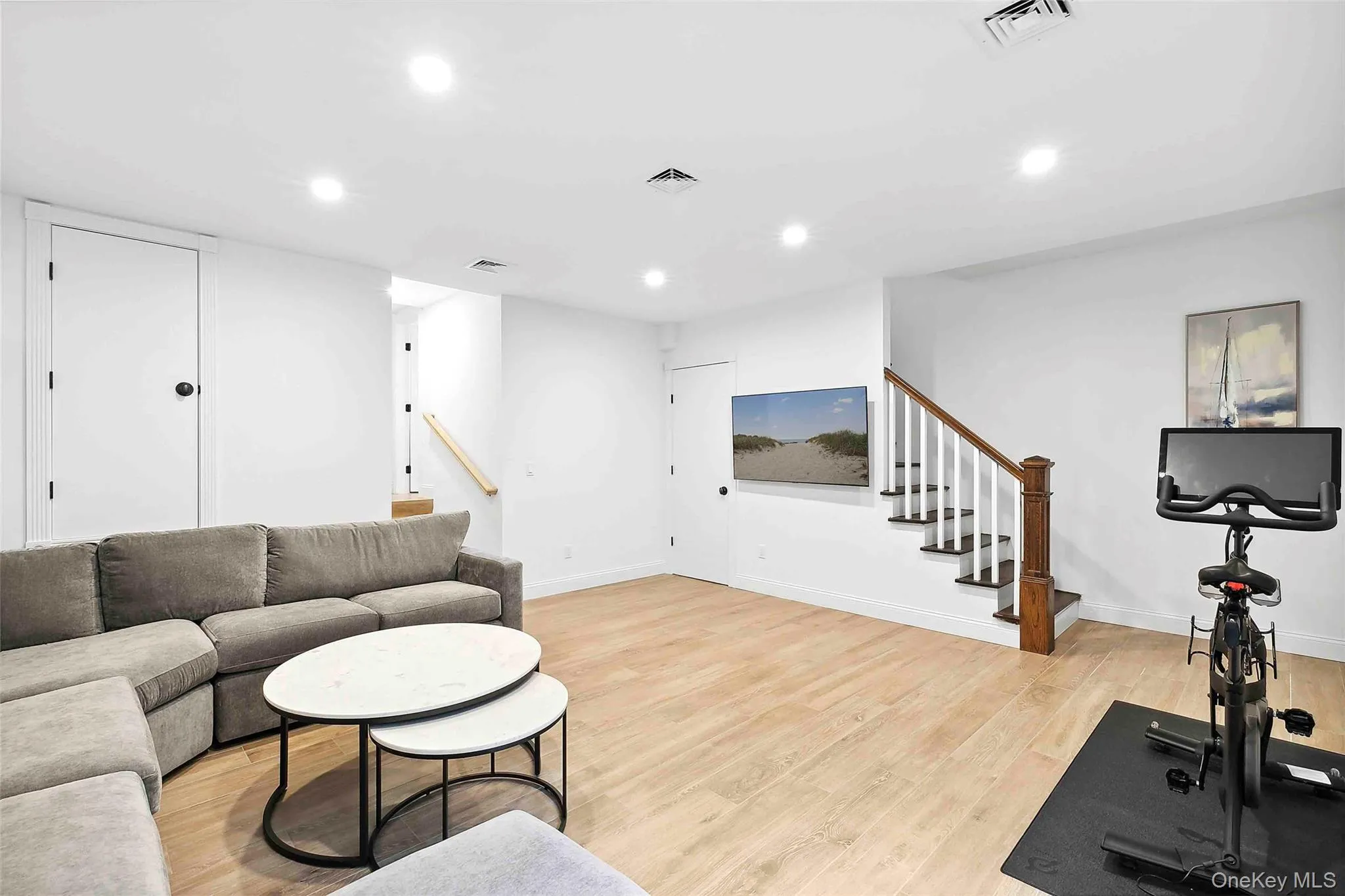 Living area with stairway, light wood-style flooring, and recessed lighting Living area with stairway, light wood-style flooring, and recessed lighting