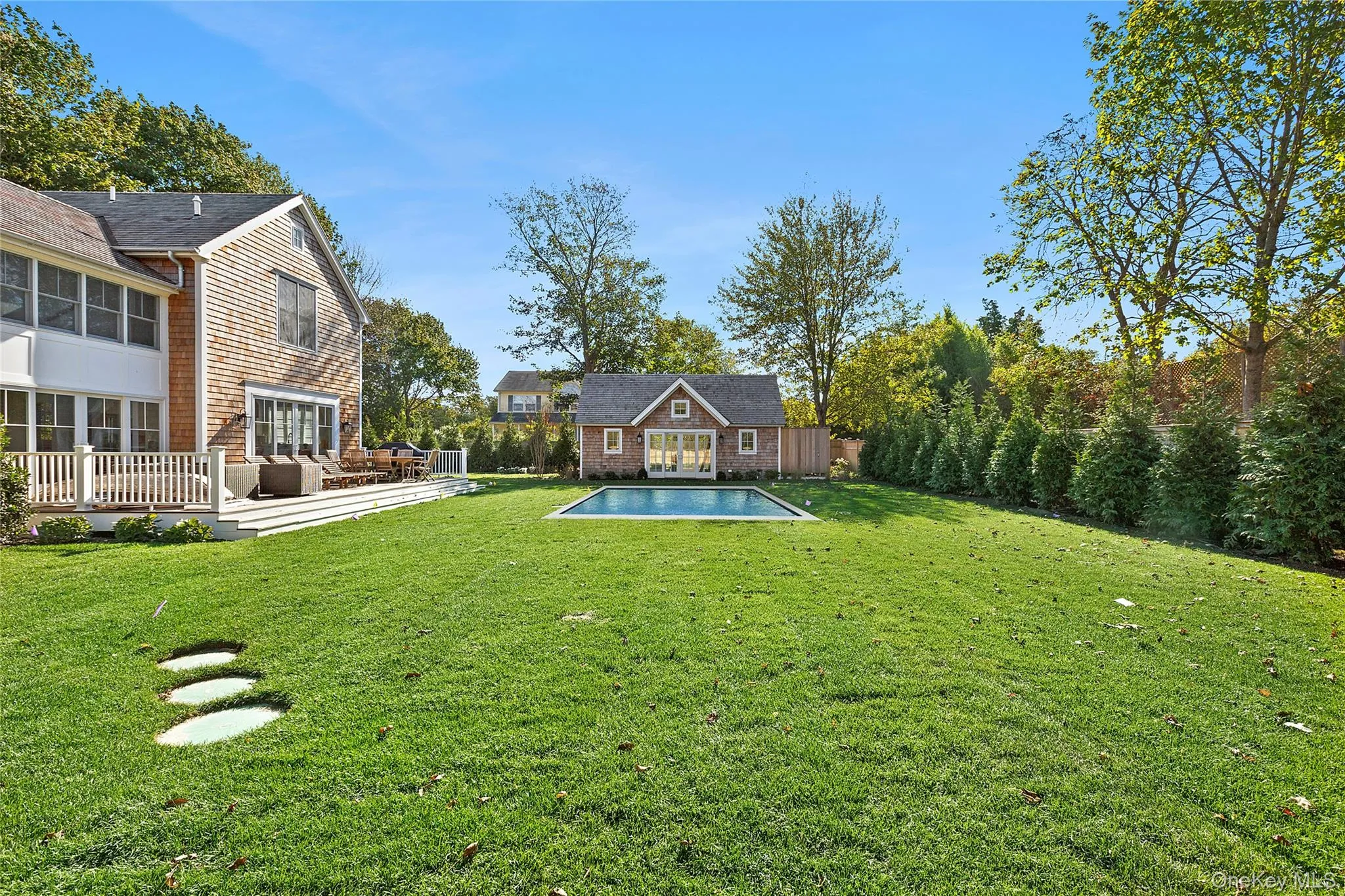 View of grassy yard featuring an outdoor structure, a deck, an exterior structure, an outdoor pool, and a patio View of grassy yard featuring an outdoor structure, a deck, an exterior structure, an outdoor pool, and a patio