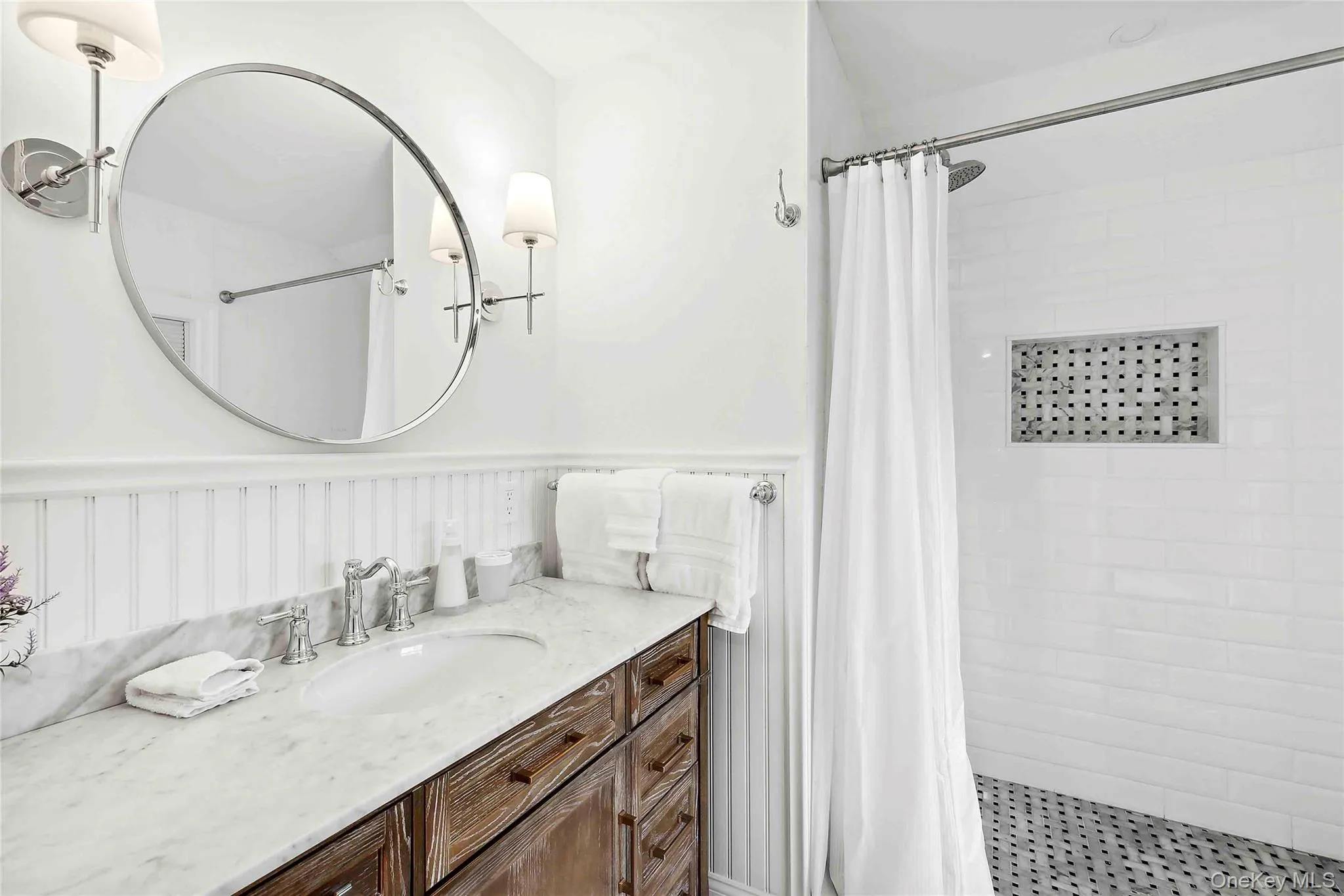 Full bath featuring a shower stall, vanity, and a wainscoted wall Full bath featuring a shower stall, vanity, and a wainscoted wall