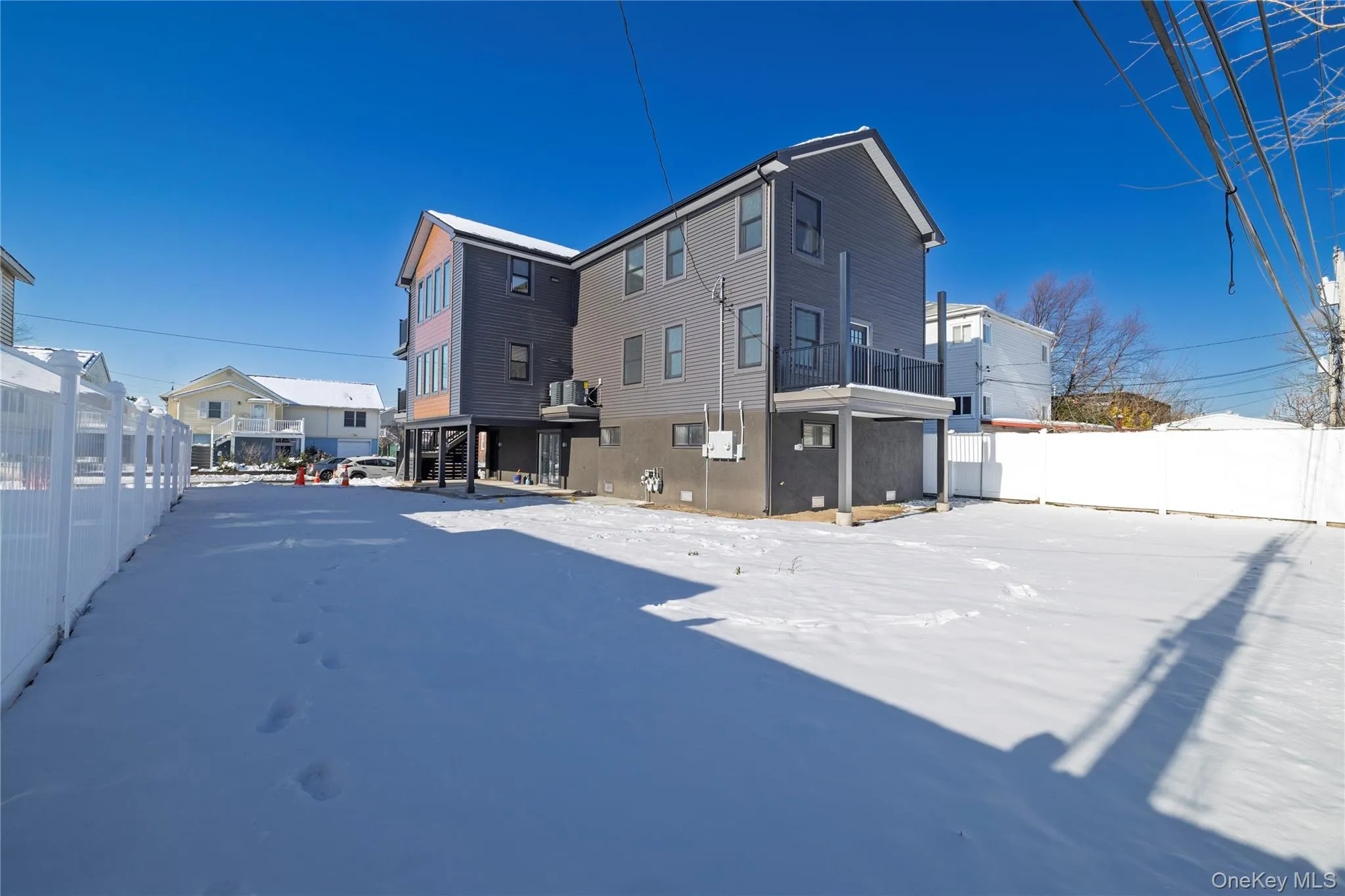 Snow covered back of property with a fenced backyard and a balcony Snow covered back of property with a fenced backyard and a balcony