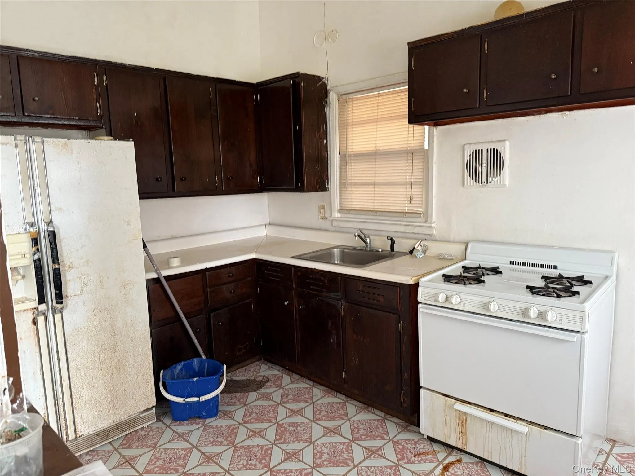 Kitchen with dark brown cabinets, white appliances, light countertops, and light flooring Kitchen with dark brown cabinets, white appliances, light countertops, and light flooring