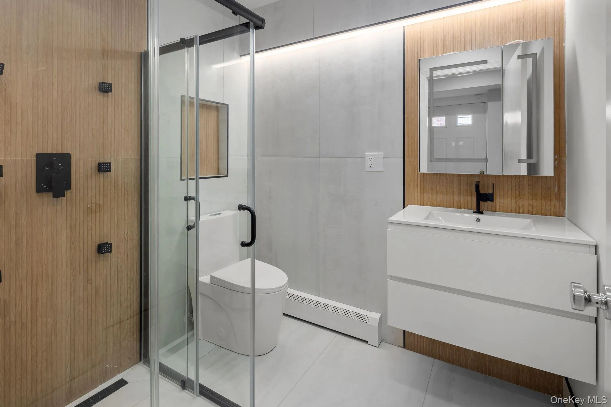 Bathroom with a baseboard radiator, tile patterned flooring, toilet, a shower with door, and vanity Bathroom with a baseboard radiator, tile patterned flooring, toilet, a shower with door, and vanity