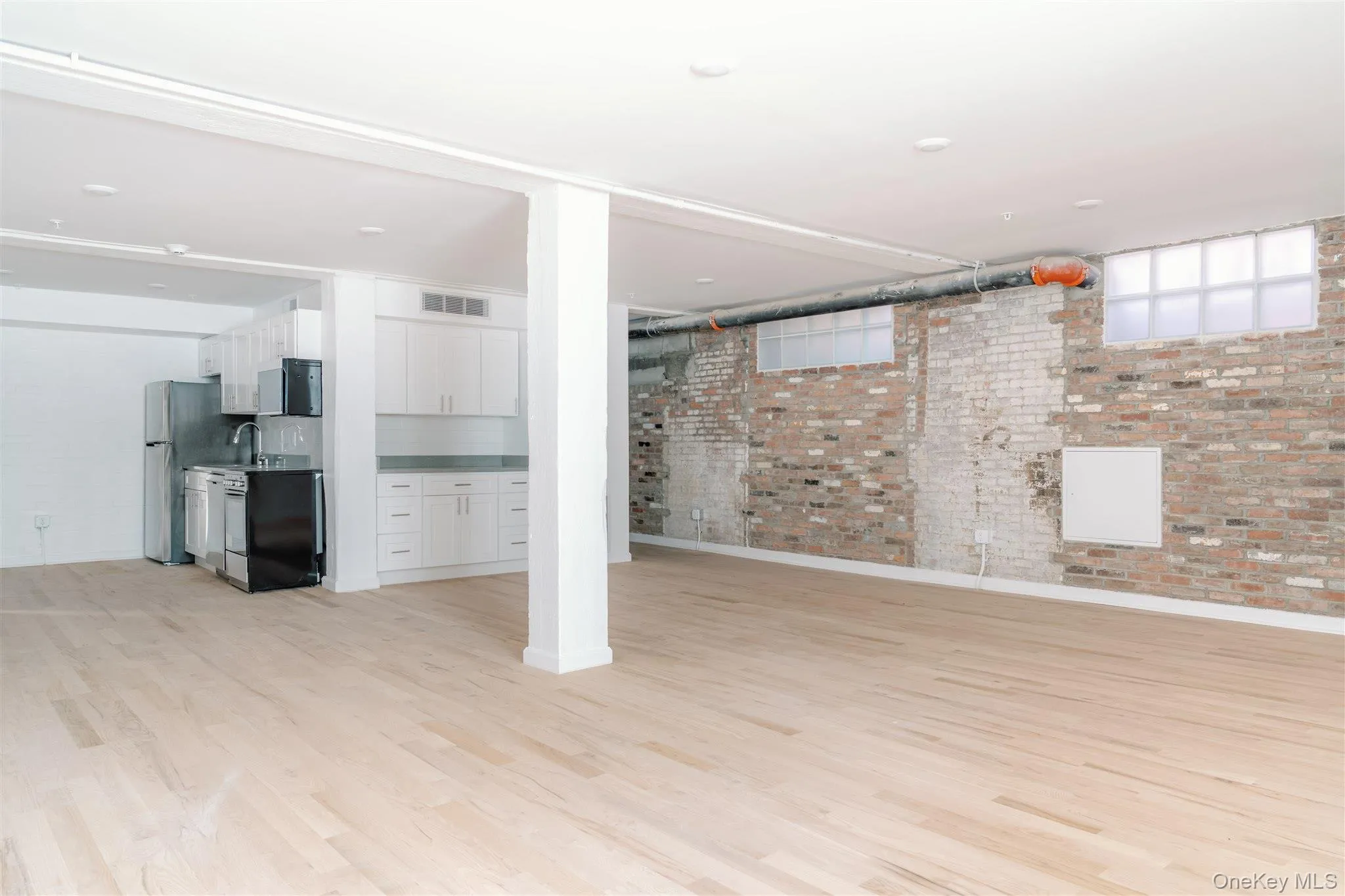Below grade area featuring brick wall and light wood-style flooring Below grade area featuring brick wall and light wood-style flooring