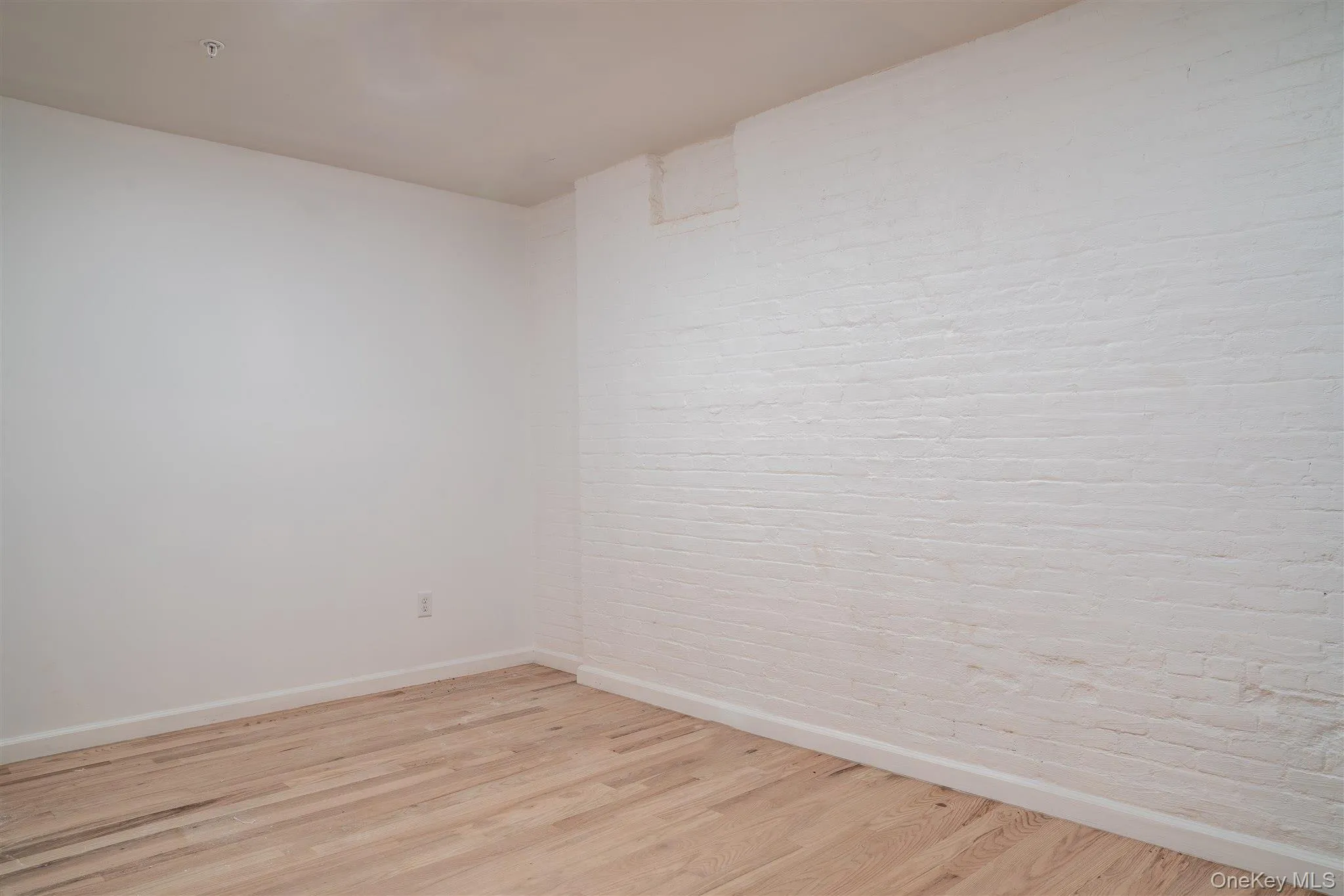 Empty room with light wood-style floors and baseboards Empty room with light wood-style floors and baseboards