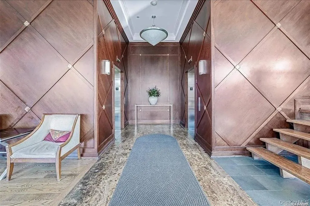 Corridor featuring ornamental molding, stairway, and elevator Corridor featuring ornamental molding, stairway, and elevator