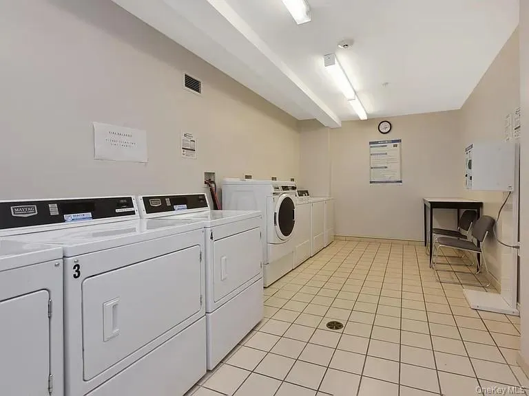 Community laundry with washing machine and dryer and light tile patterned floors Community laundry with washing machine and dryer and light tile patterned floors