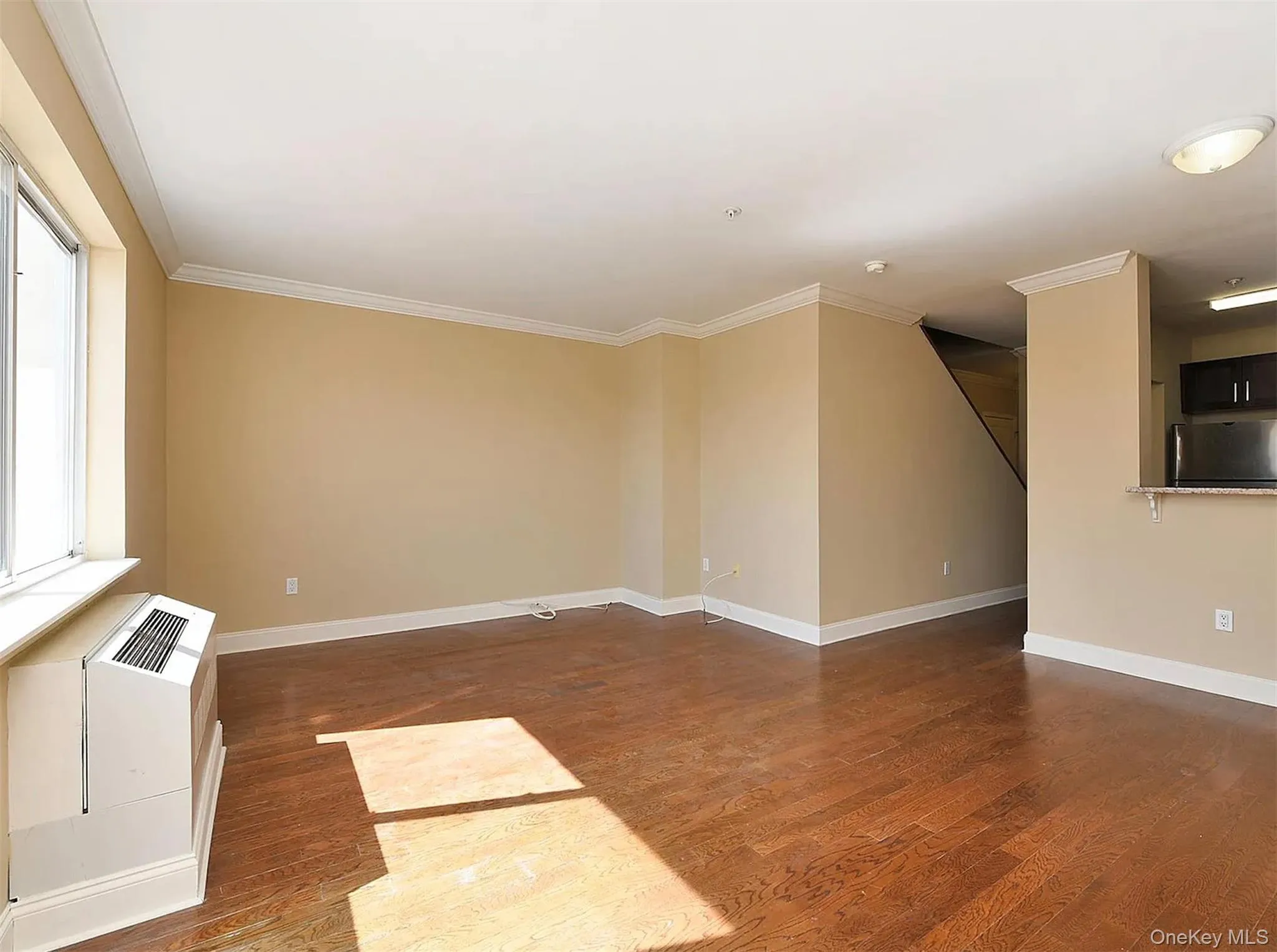 Unfurnished living room with wood finished floors and ornamental molding Unfurnished living room with wood finished floors and ornamental molding