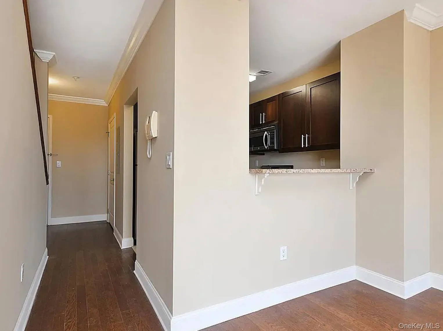 Hall with ornamental molding and dark wood finished floors Hall with ornamental molding and dark wood finished floors