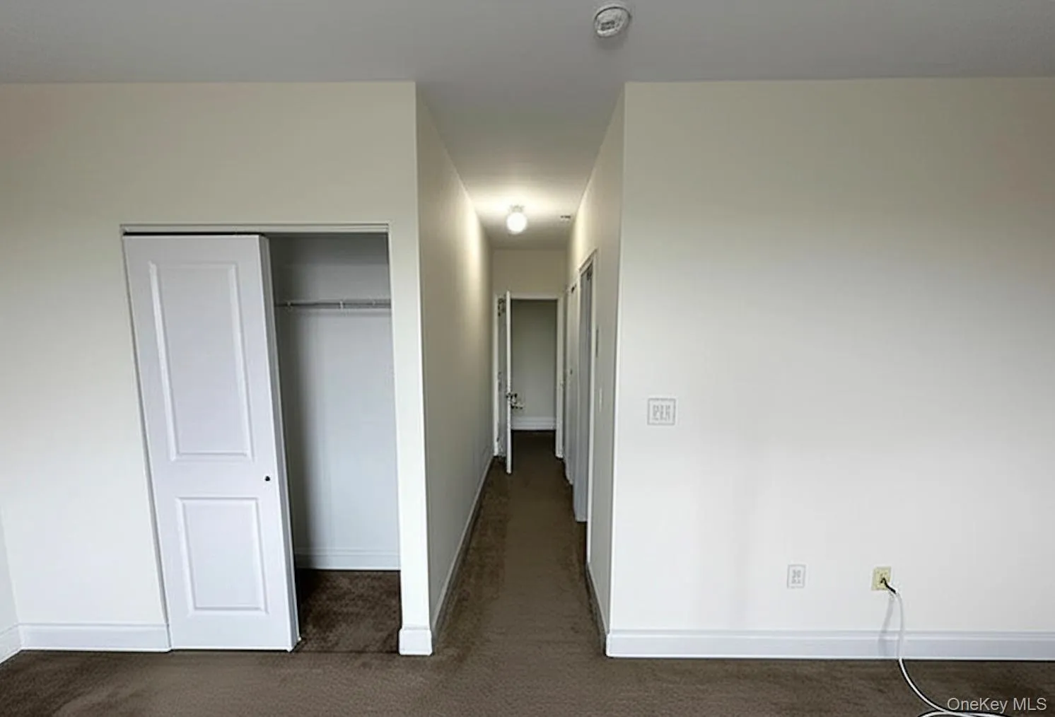 Hall with baseboards and dark carpet Hall with baseboards and dark carpet