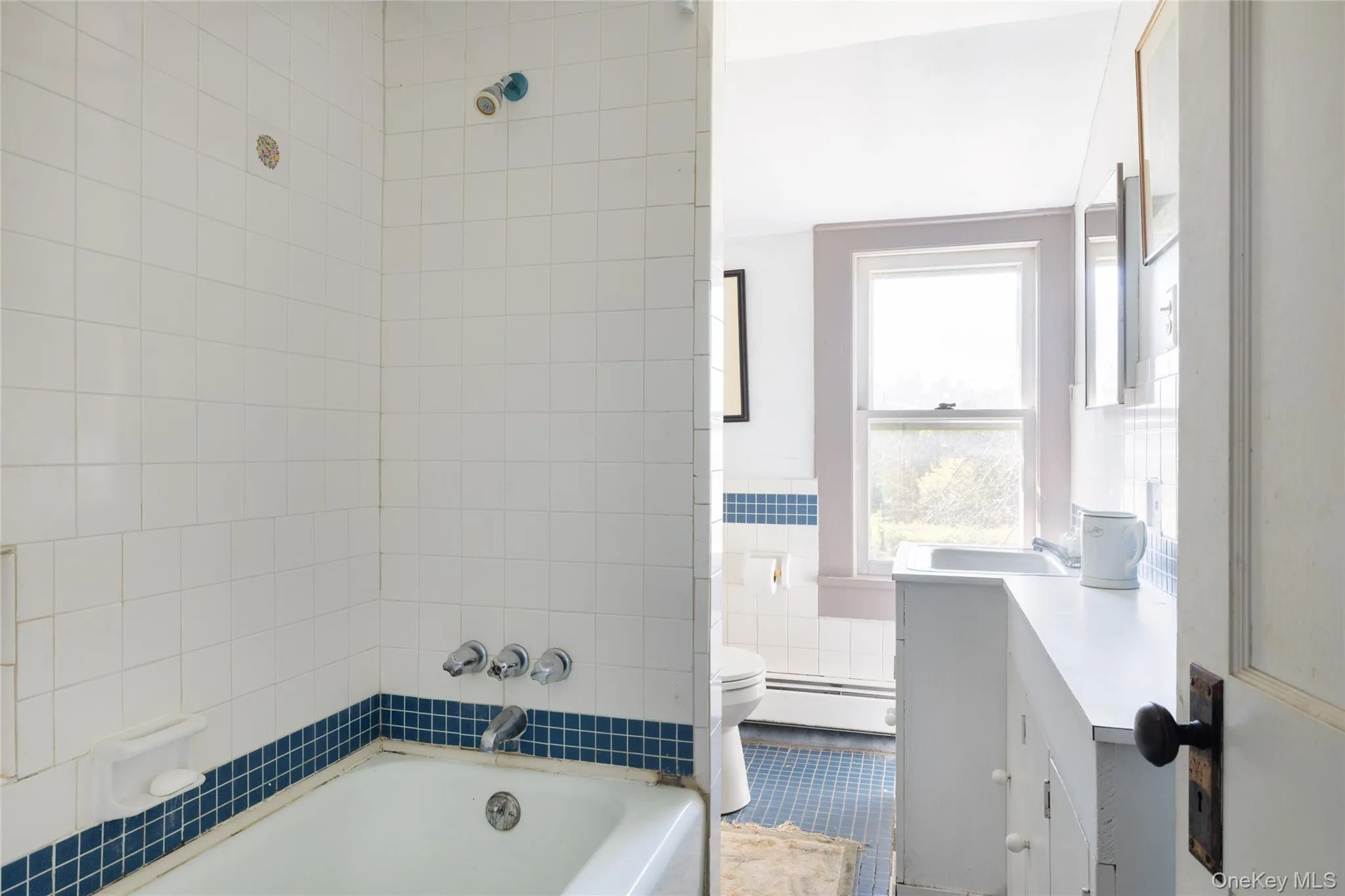 Bathroom featuring tile walls, vanity, and a combination shower/bathtub Bathroom featuring tile walls, vanity, and a combination shower/bathtub