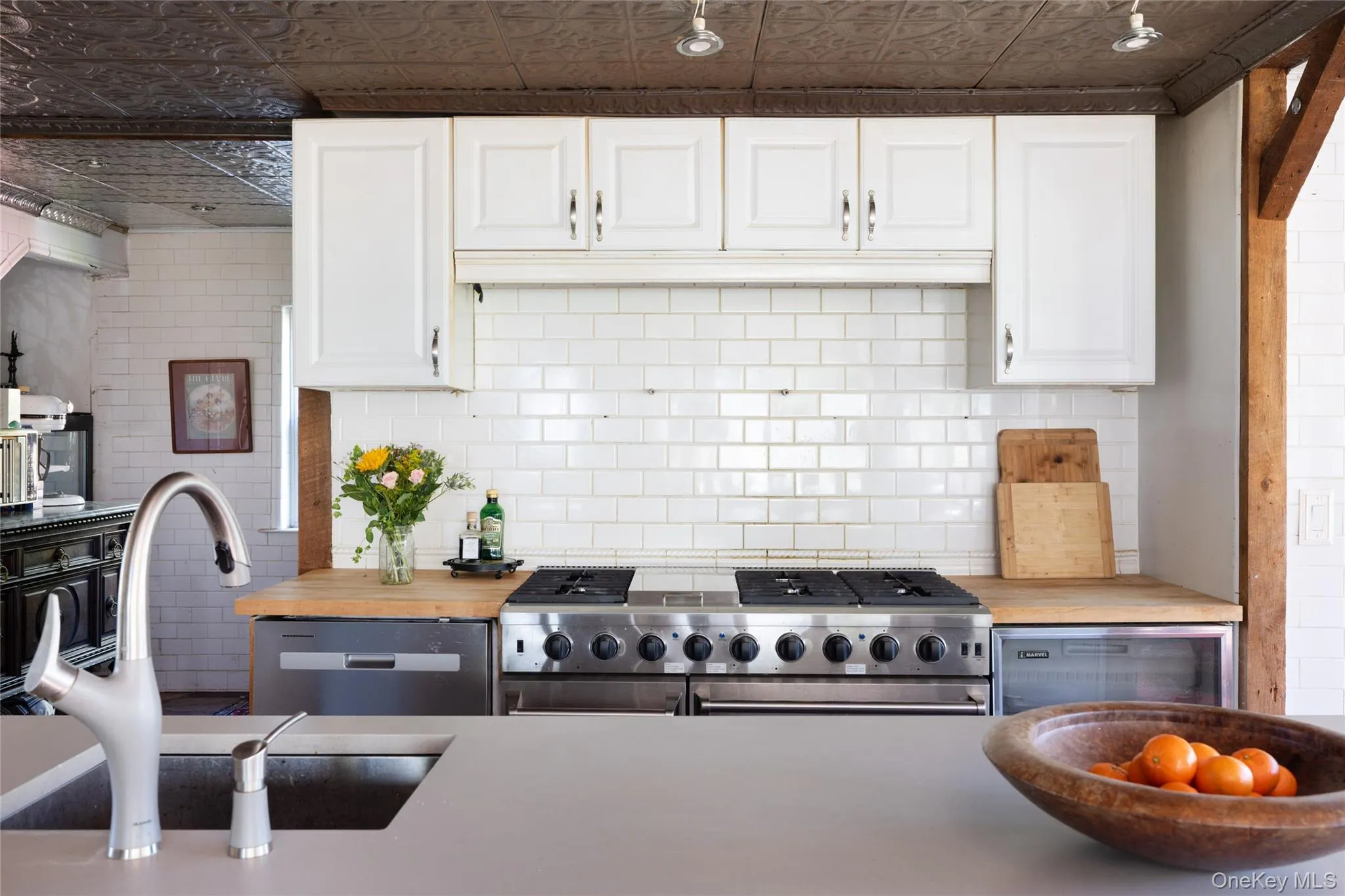 Kitchen with appliances with stainless steel finishes, white cabinets, an ornate ceiling, and tasteful backsplash Kitchen with appliances with stainless steel finishes, white cabinets, an ornate ceiling, and tasteful backsplash