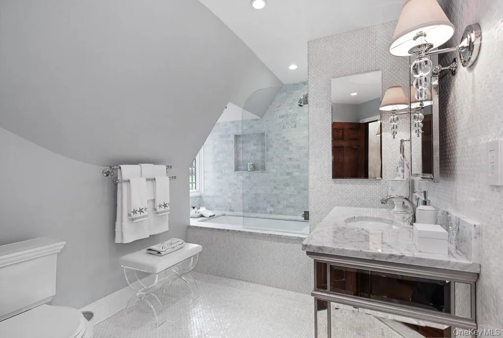 The oversized full hallway bathroom on the second level features a beautiful mosaic floor, a luxe bathtub with shower, and a mirrored vanity. The oversized full hallway bathroom on the second level features a beautiful mosaic floor, a luxe bathtub with shower, and a mirrored vanity.