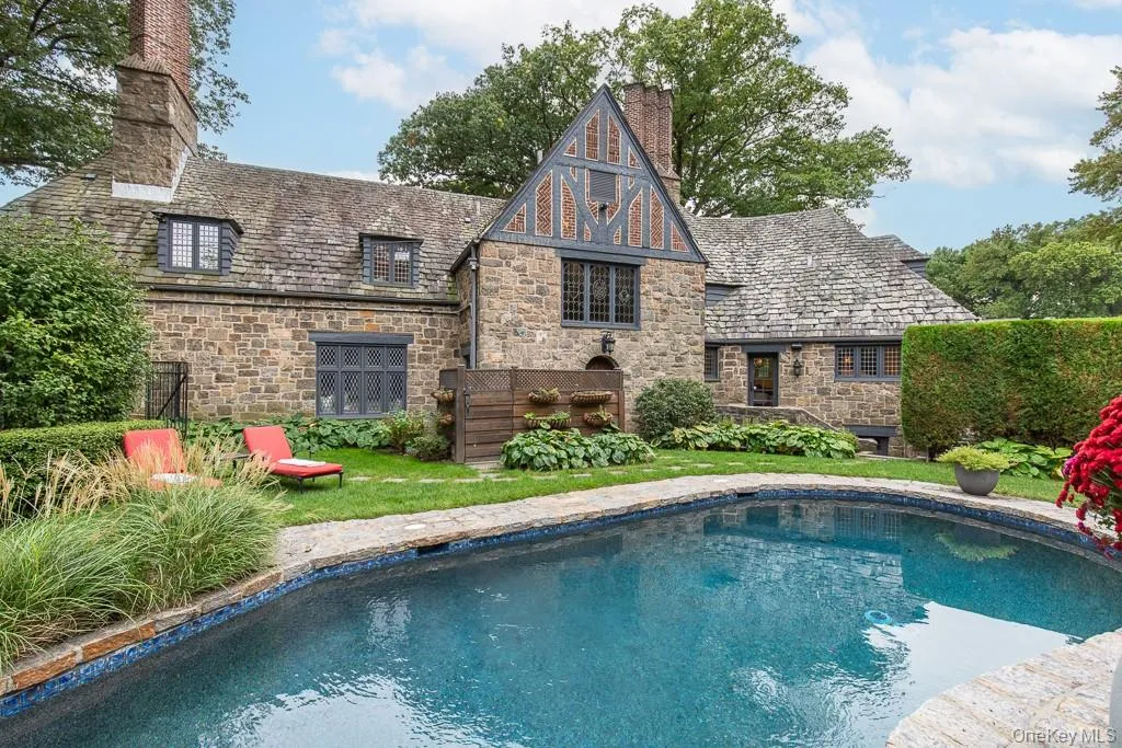A stunning view of the majestic tudor architecture, landscaping, and resort-style backyard. A stunning view of the majestic tudor architecture, landscaping, and resort-style backyard.