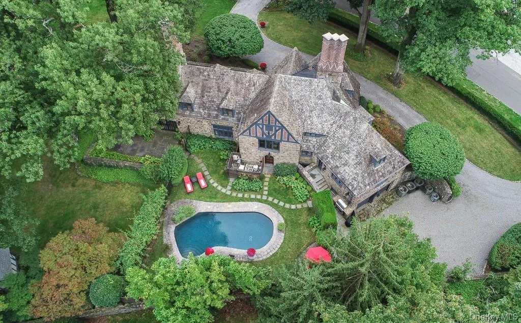 Aerial view of the nearly 1 acre setting with a pool and meticulously landscaped grounds. Aerial view of the nearly 1 acre setting with a pool and meticulously landscaped grounds.