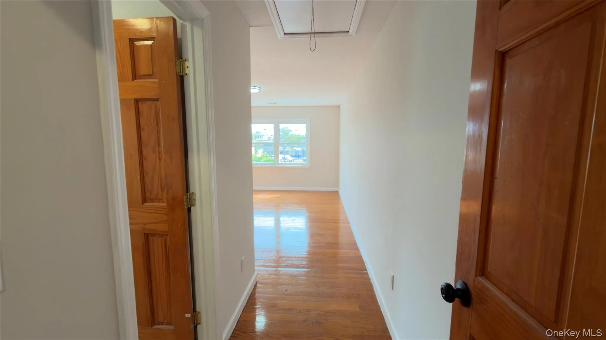 Hallway with attic access and wood finished floors Hallway with attic access and wood finished floors