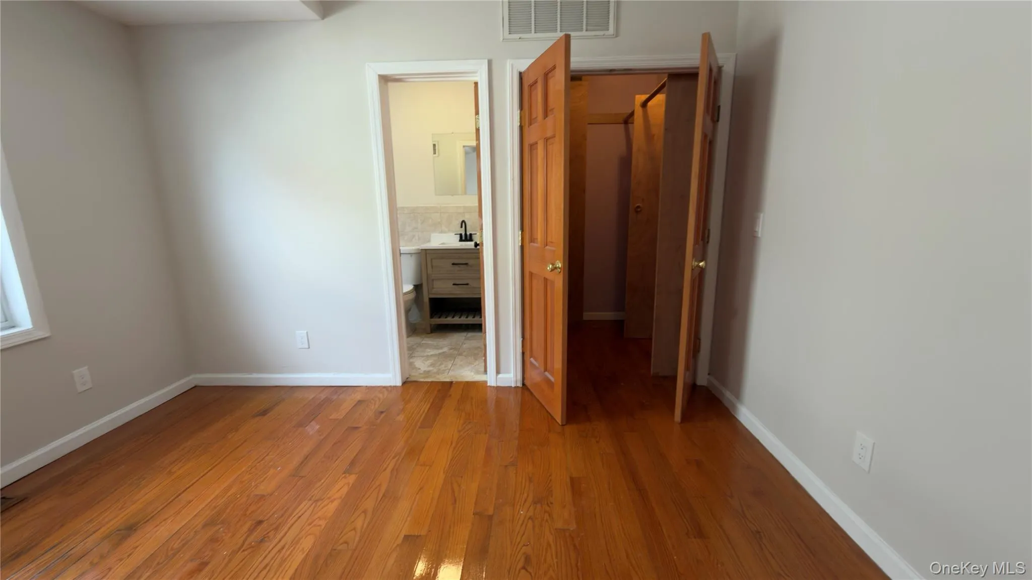 Unfurnished bedroom with wood finished floors and ensuite bathroom Unfurnished bedroom with wood finished floors and ensuite bathroom