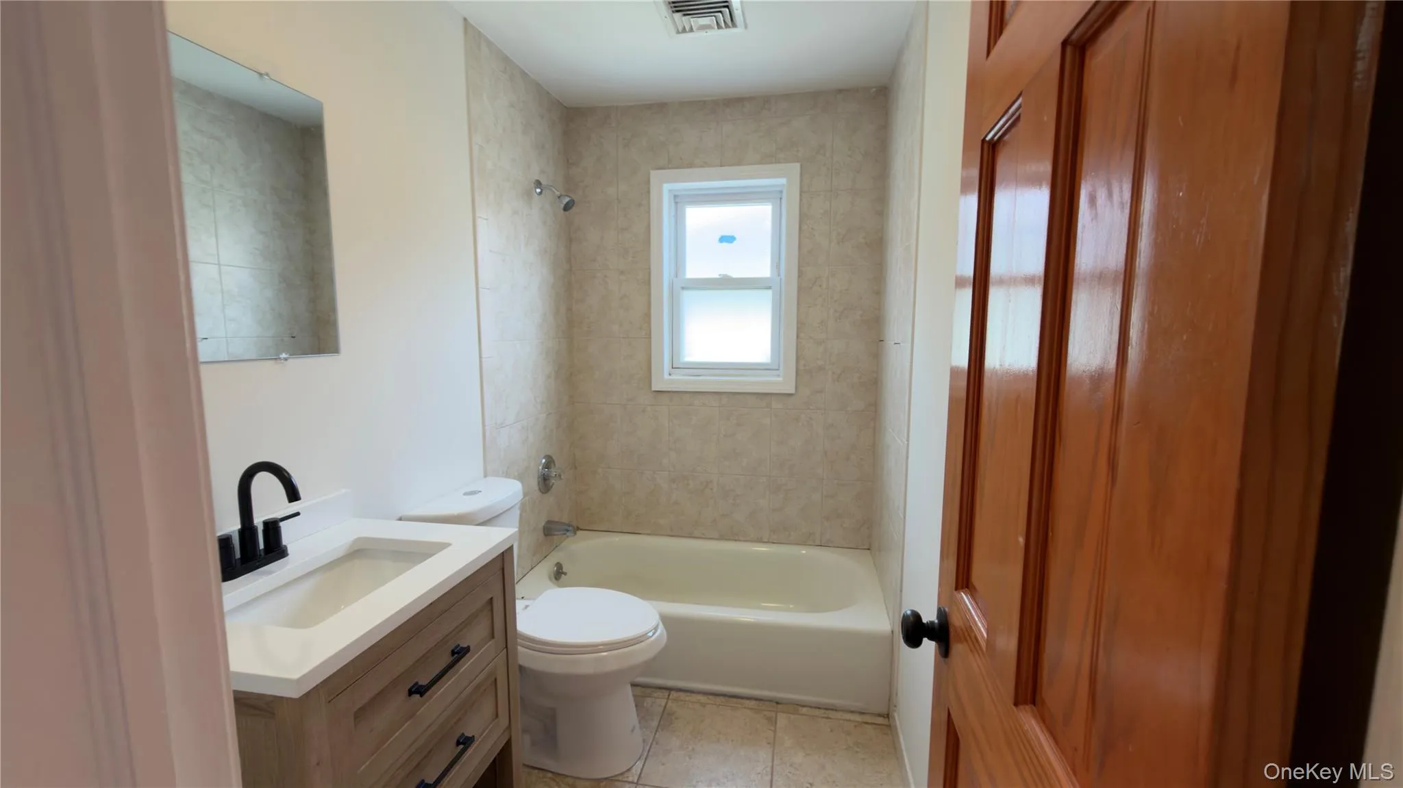 Full bath featuring vanity, bathing tub / shower combination, and light tile patterned floors Full bath featuring vanity, bathing tub / shower combination, and light tile patterned floors