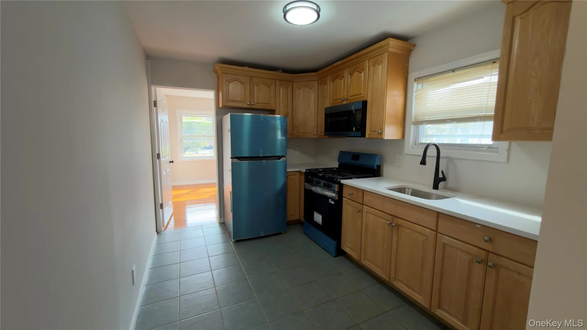 Kitchen featuring gas stove, freestanding refrigerator, plenty of natural light, and black microwave Kitchen featuring gas stove, freestanding refrigerator, plenty of natural light, and black microwave