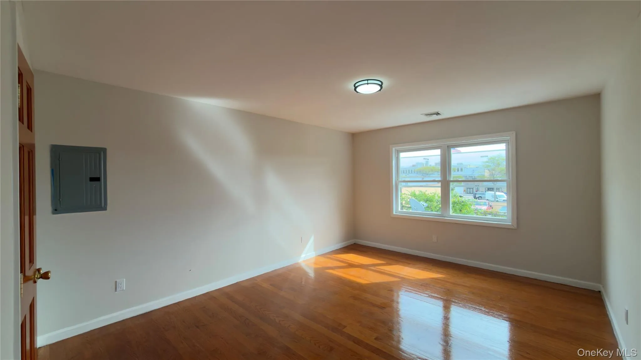 Unfurnished room with electric panel and wood finished floors Unfurnished room with electric panel and wood finished floors